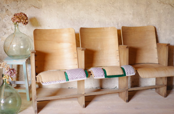 Fauteuils de cinéma vintage en bois des années 50, assise retapissée avec toile de jute, tissu au motif graphique, ponctuée de velours vert pour un esprit industriel et tribal.