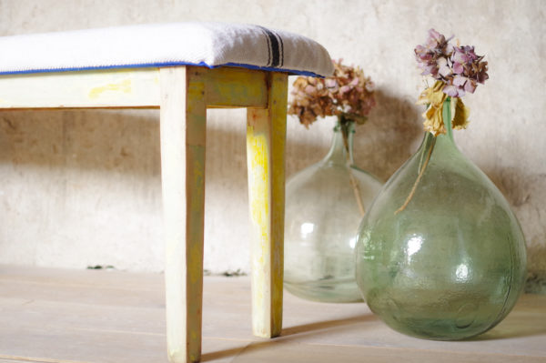 Banc en bois patine superbe, assise en métis ancien blanc traversé d'une rayure. Style graphique et décontracté.