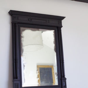 Ce miroir ancien en bois sculpté est mercurisé et son tain est largement patiné sur les pourtours.