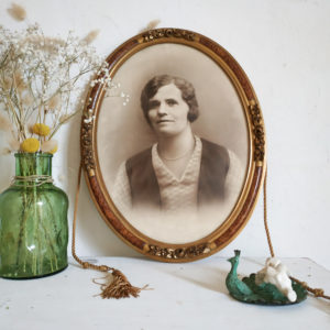 Voici un portrait de femme du début du siècle dernier dans un cadre en forme de médaillon.