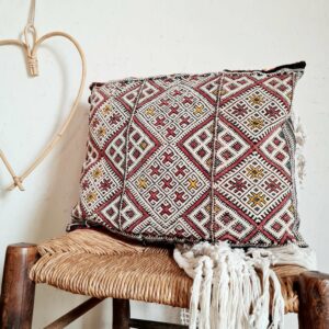 Ce coussin ancien réalisé à la main arbore avec plaisir des broderies contrastantes ikat, aux motifs géométriques et colorés.