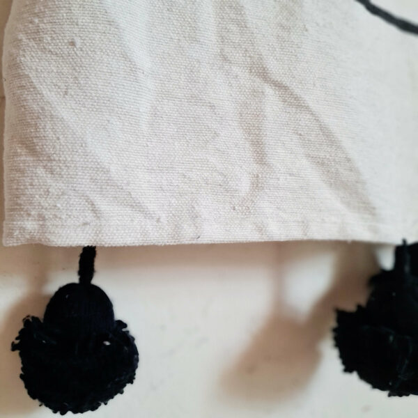 Plaid en coton blanc avec rayures noires et pompons en laine de couleur noir