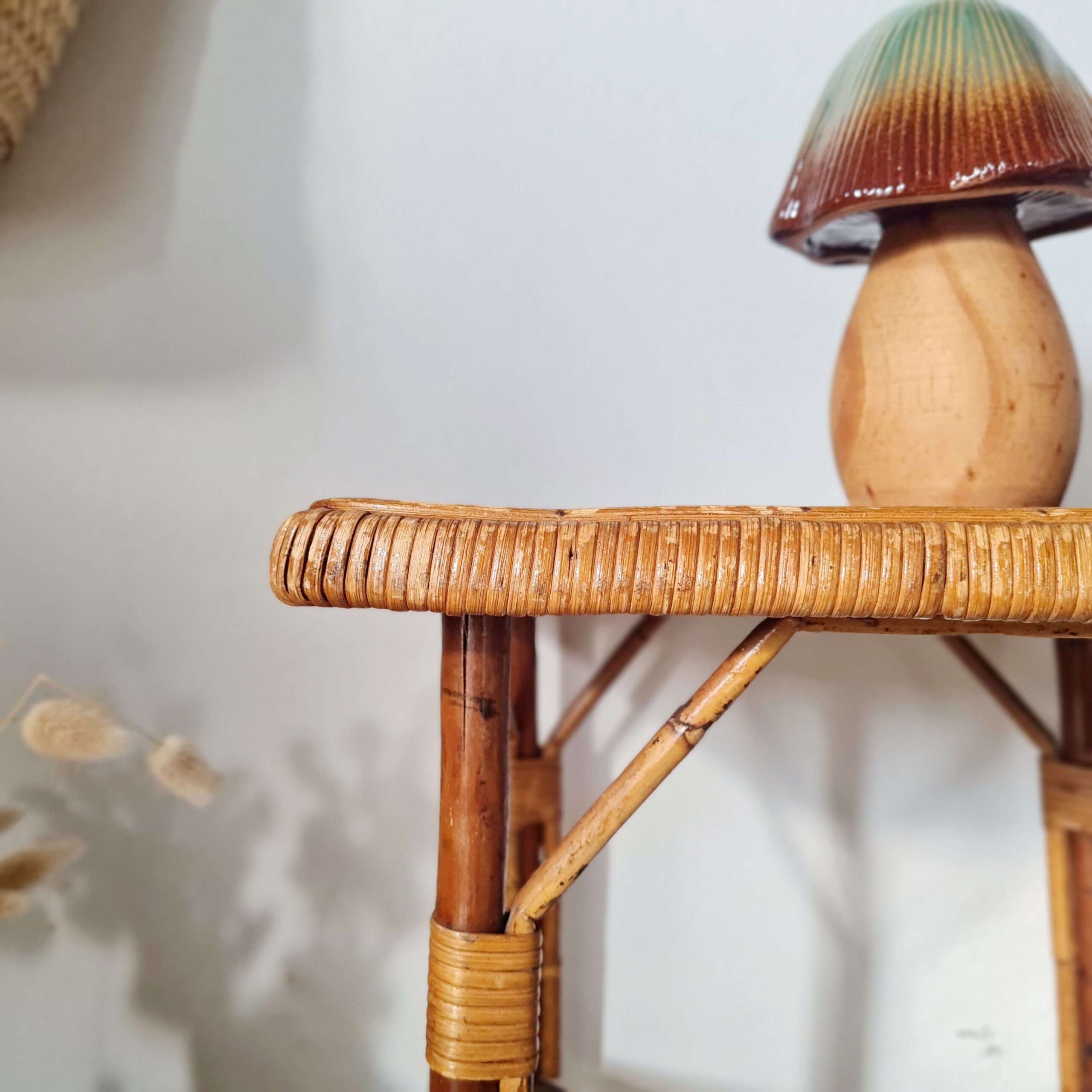 Gros plan sur les finitions et les ligatures en éclisse de rotin d'une table d'appoint ancienne, mettant en valeur le travail artisanal.