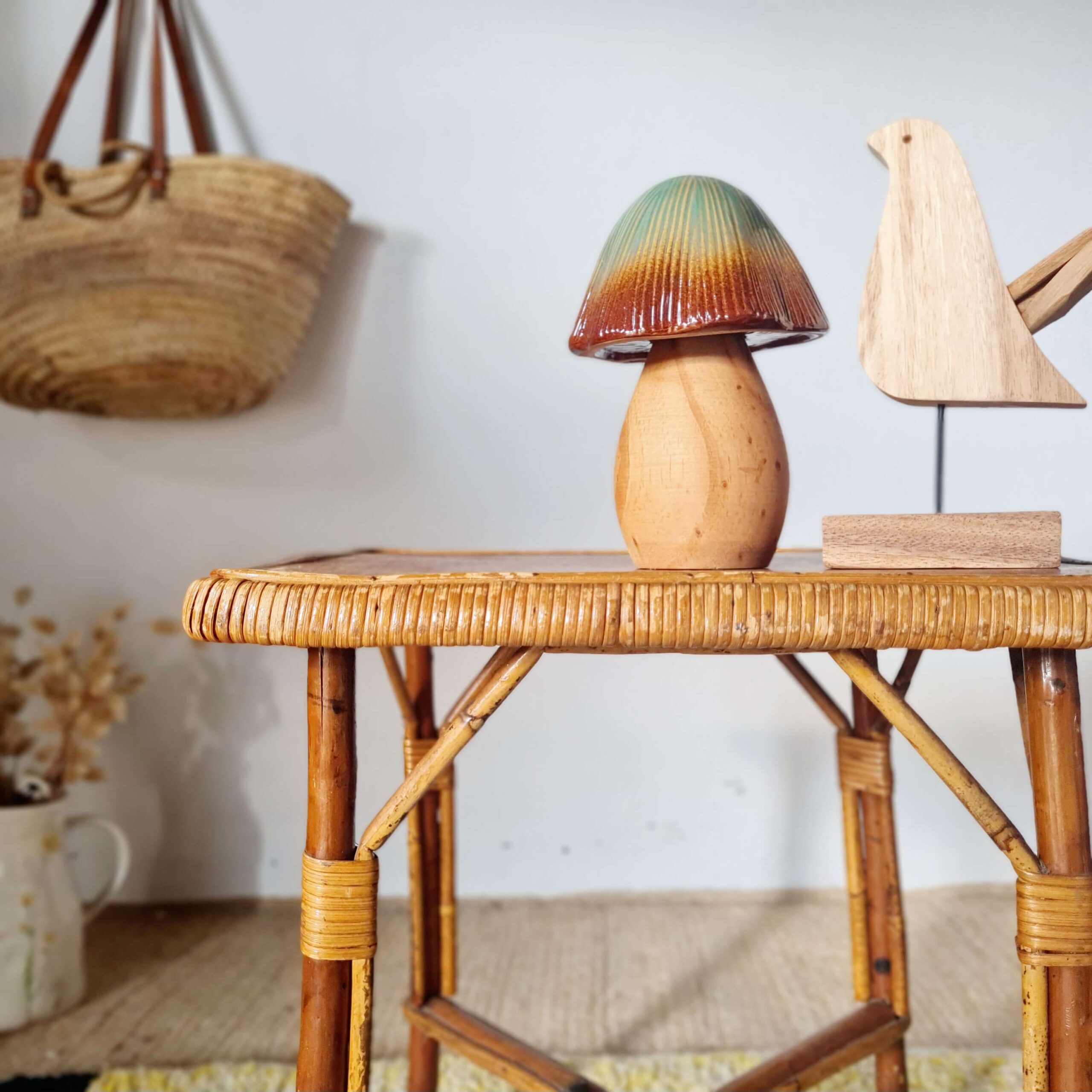 Focus sur la partie haute d'une table basse rétro, mettant en valeur la texture du rotin tressé et les bibelots décoratifs posés sur le meuble.