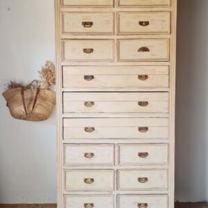 Vue d'ensemble d'un ancien meuble de mercerie en bois patiné avec de multiples tiroirs, idéal pour le rangement vintage