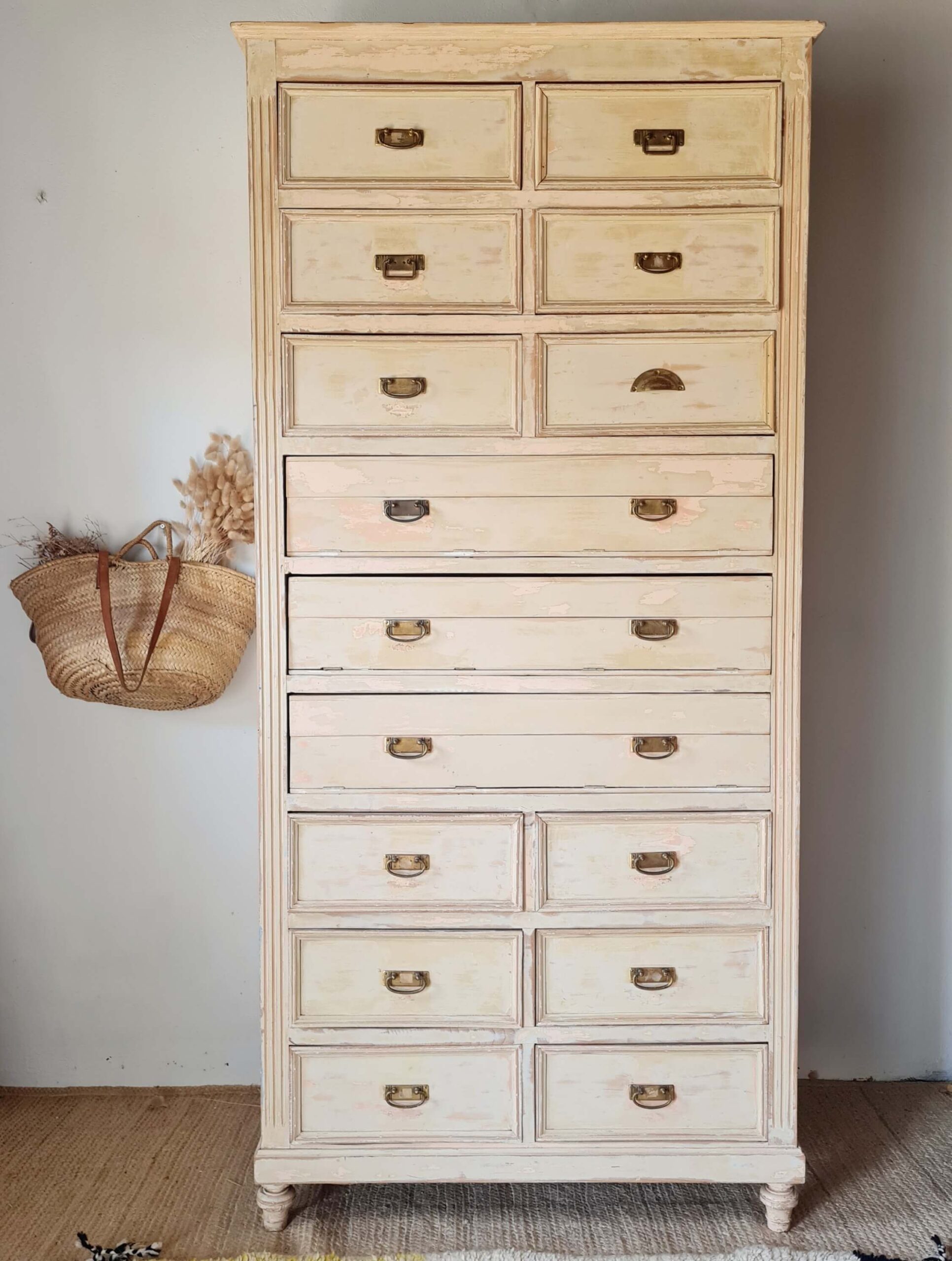 Vue d'ensemble d'un ancien meuble de mercerie en bois patiné avec de multiples tiroirs, idéal pour le rangement vintage