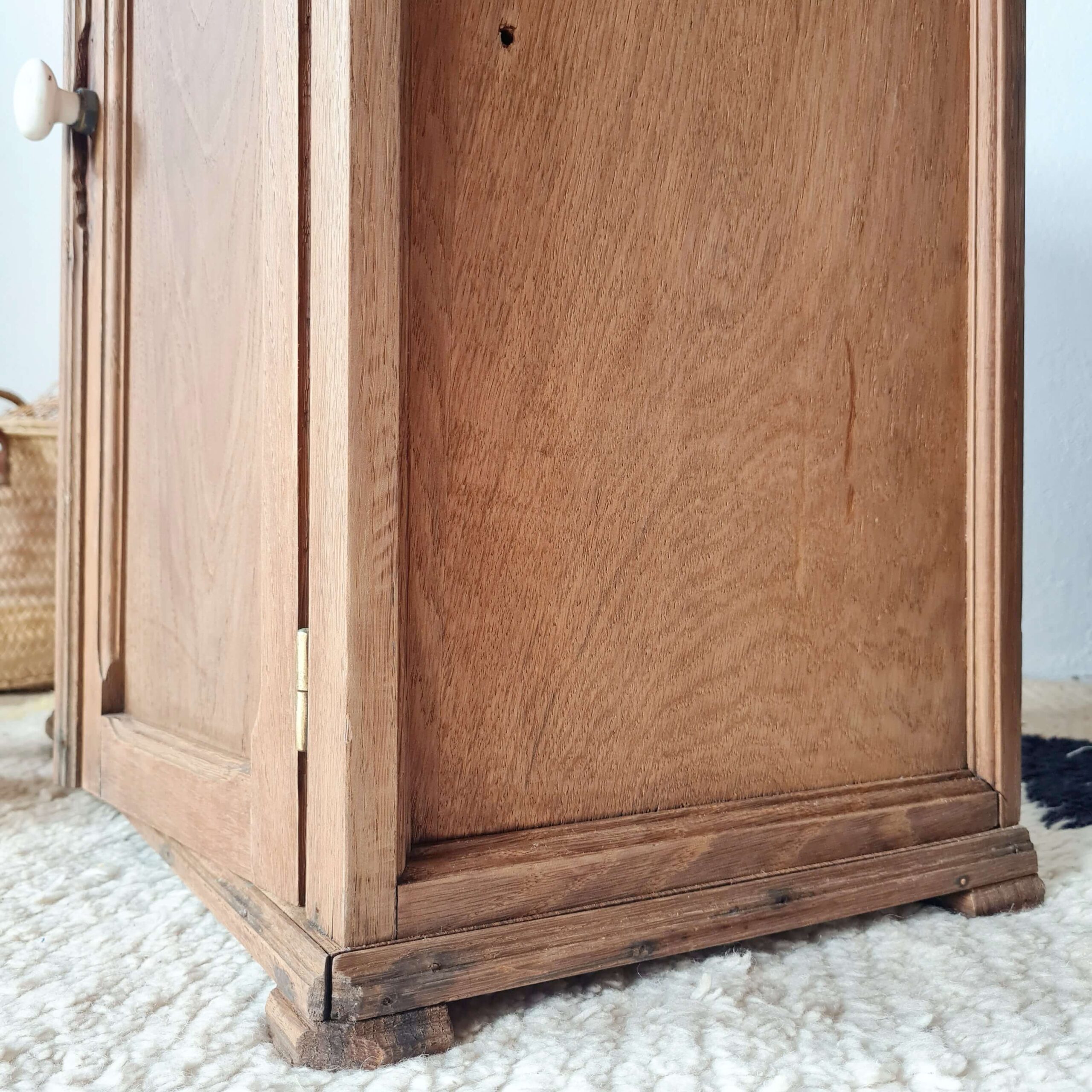 Détail de la patine du bois, de la plinthe et du panneau latéral d'une petite armoire de pharmacie vintage
