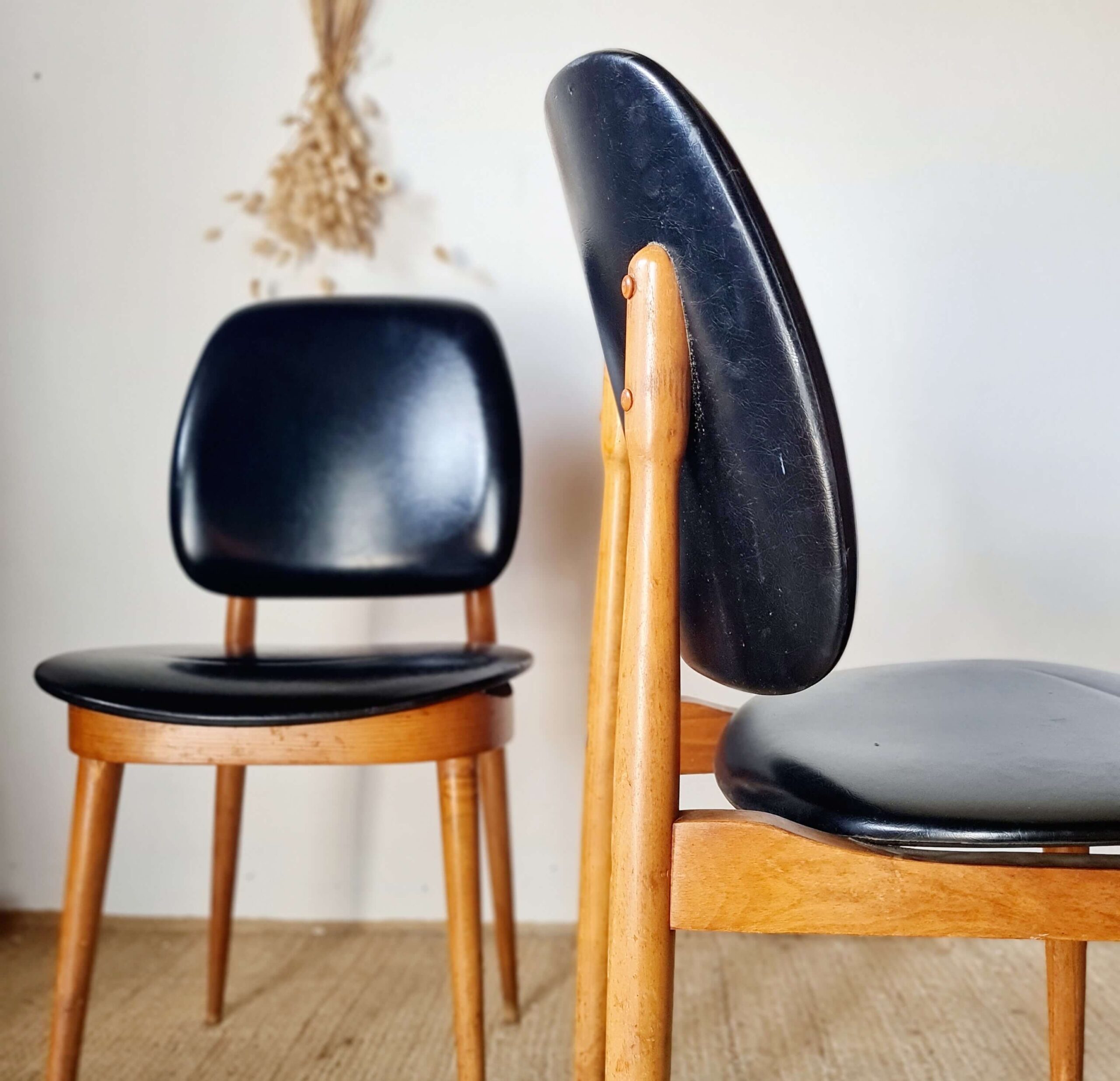 Gros plan sur le profil en bois d'une chaise vintage avec une seconde chaise en arrière-plan flou, style Mid-Century.