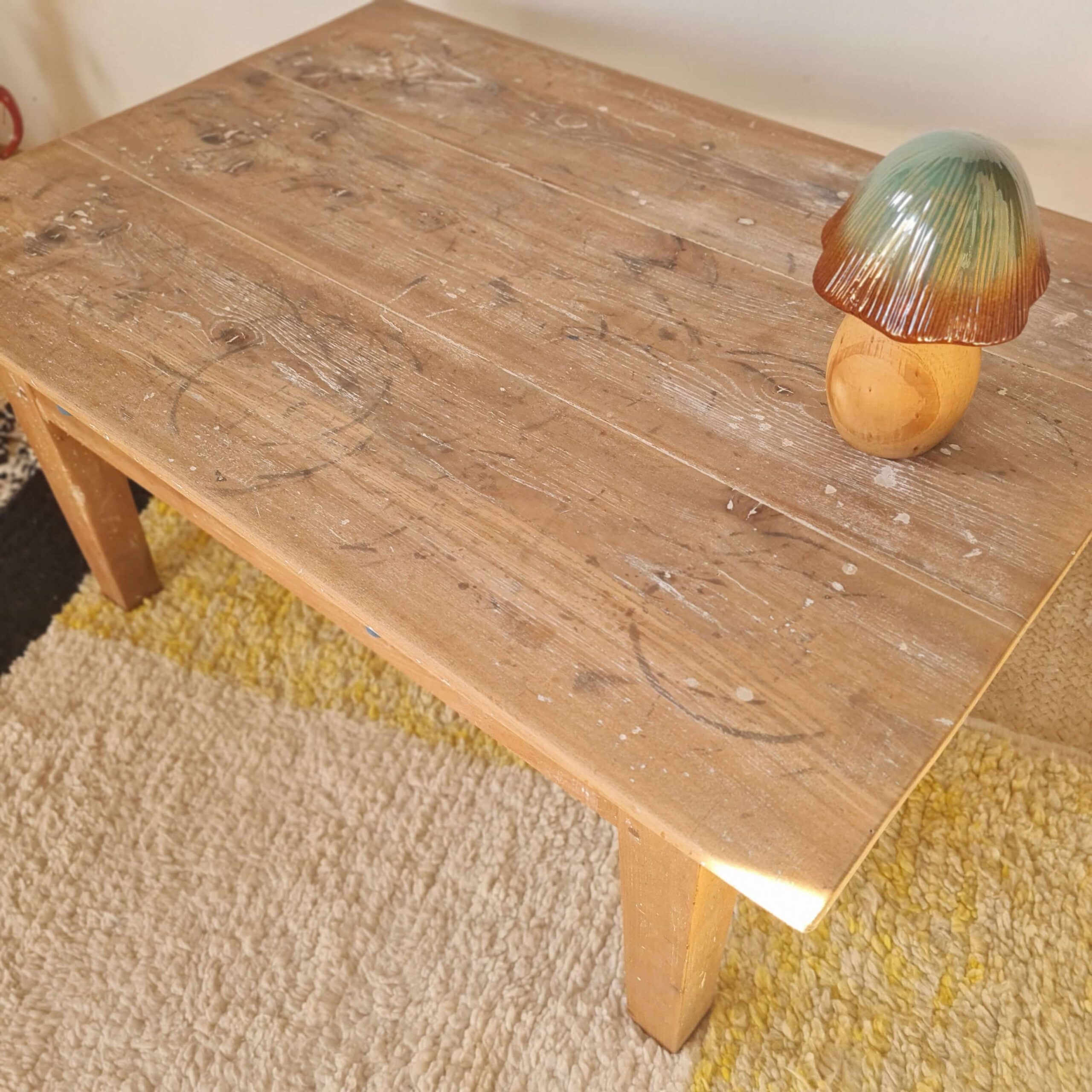Vue en contre-plongée du plateau en bois brut d'une table basse ancienne avec un champignon décoratif