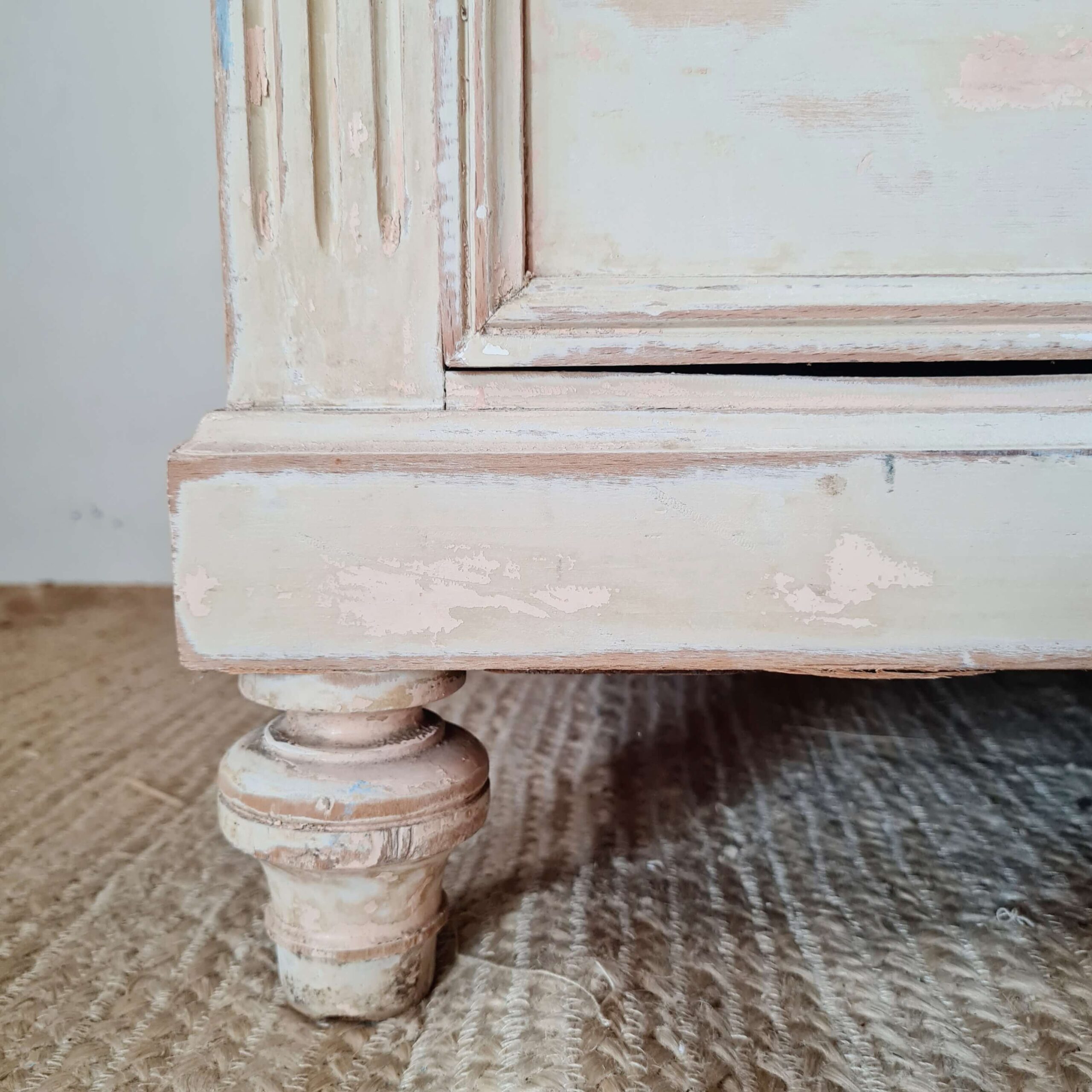 Vue rapprochée de la base d'un meuble de métier ancien, témoignant de son authenticité et de son usage passé.