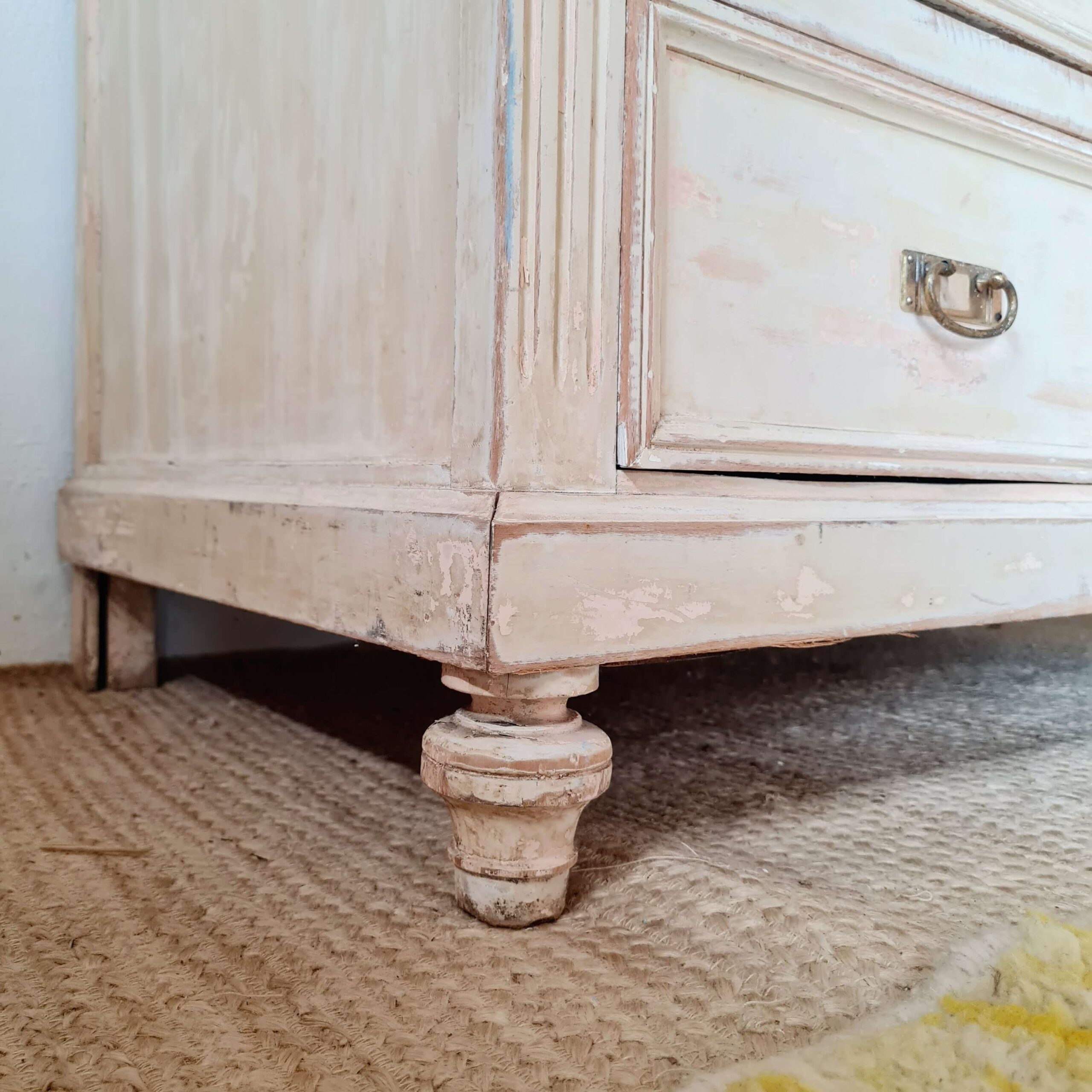 Gros plan sur le pied tourné en bois à la base de ce meuble de mercerie authentique.