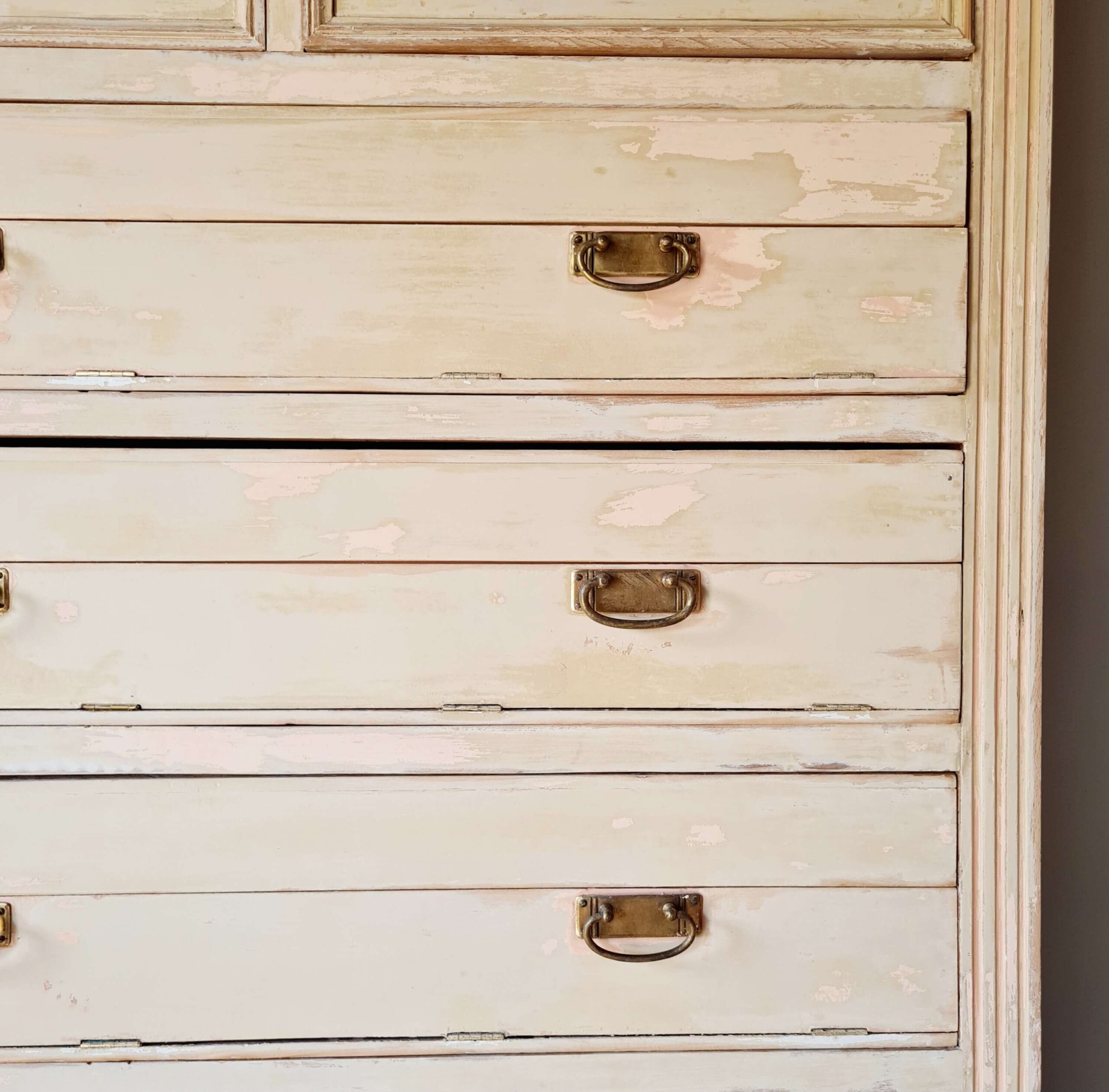 Détail d'un tiroir ouvert rempli d'un plaid en coton, illustrant les possibilités de rangement de ce meuble ancien.