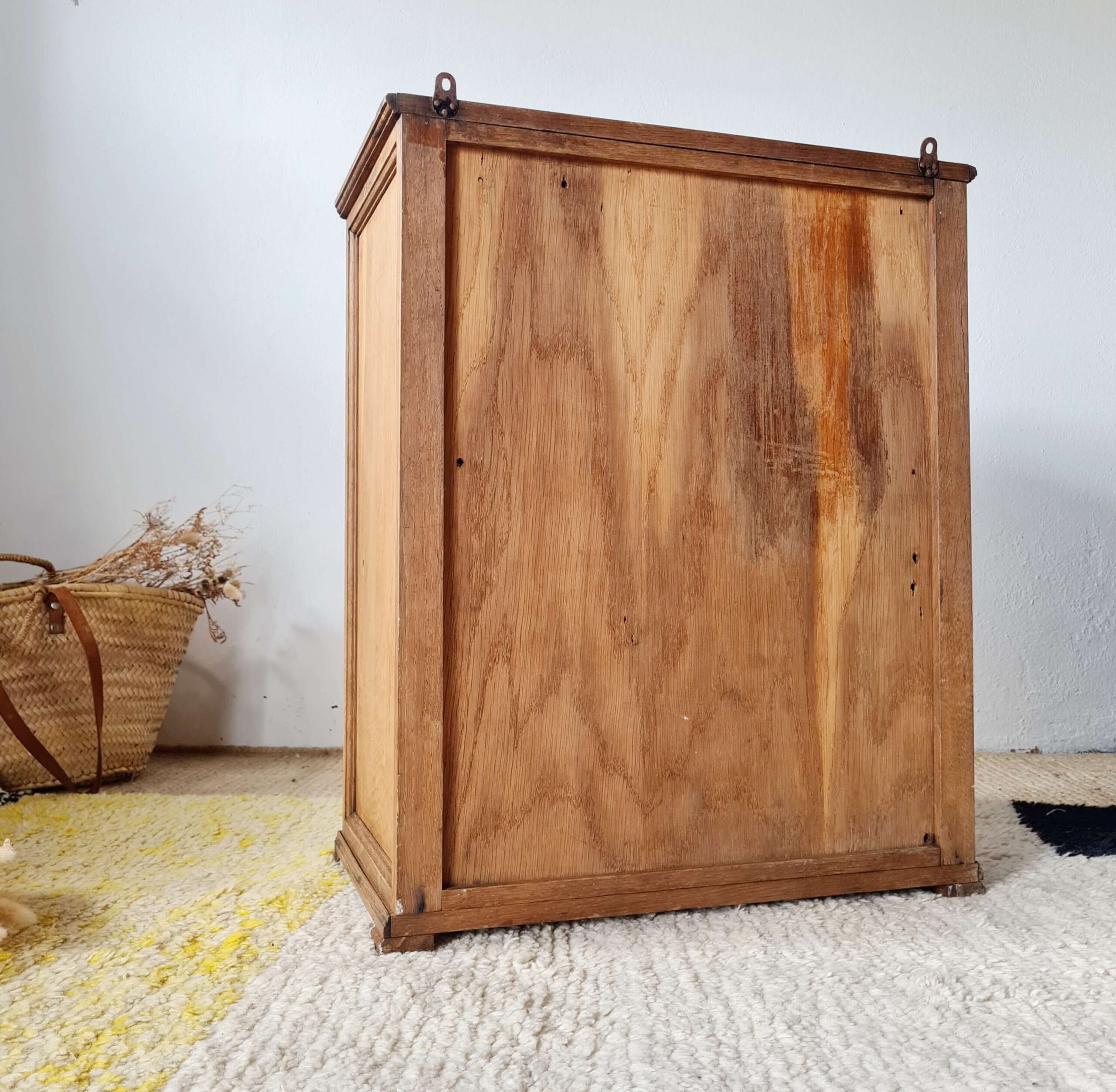 Vue arrière du panneau en bois d'une armoire parisienne vintage montrant les deux crochets de fixation murale d'origine.