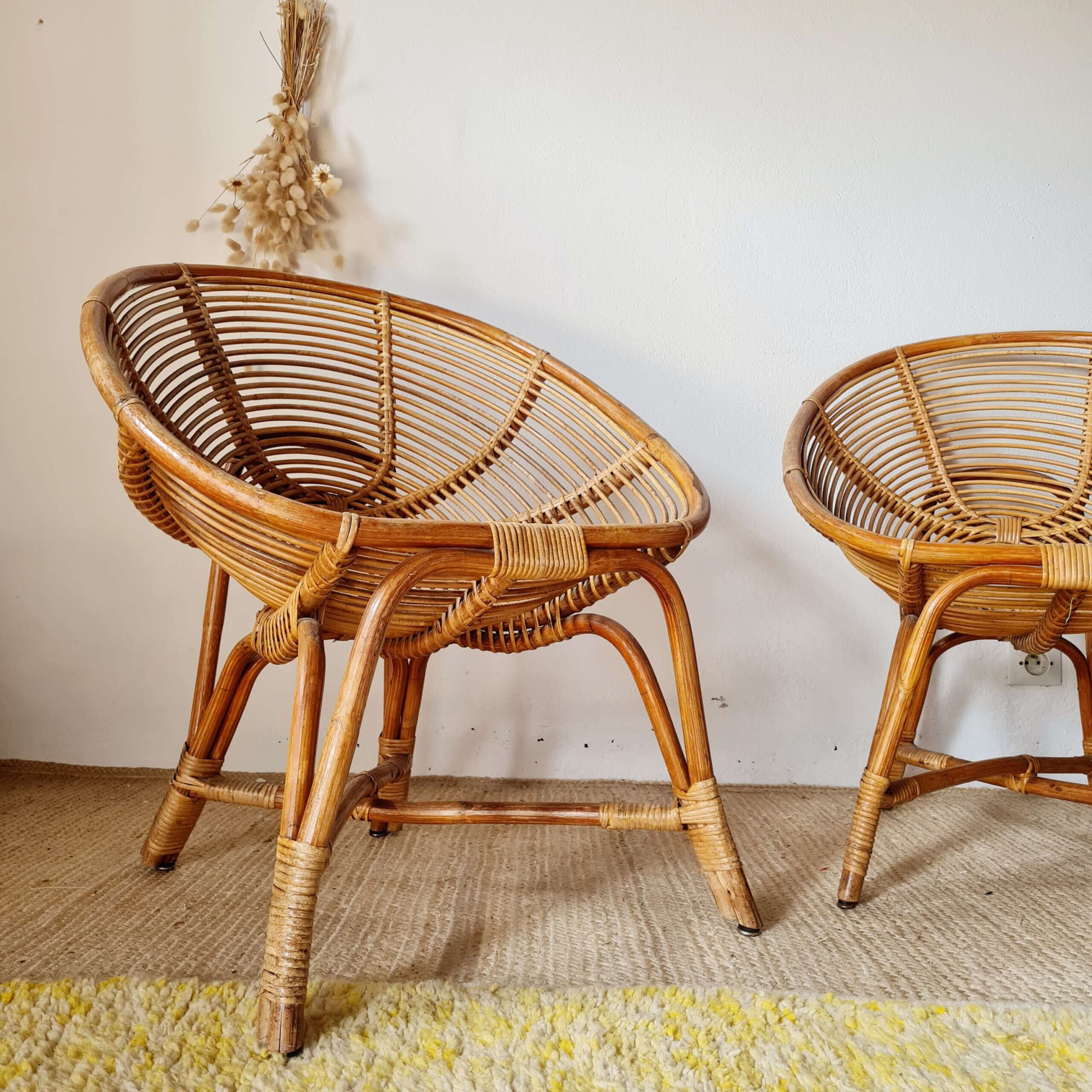 Paire de fauteuils vintage en rotin naturel aux formes arrondies, installés sur un tapis clair dans un intérieur bohème
