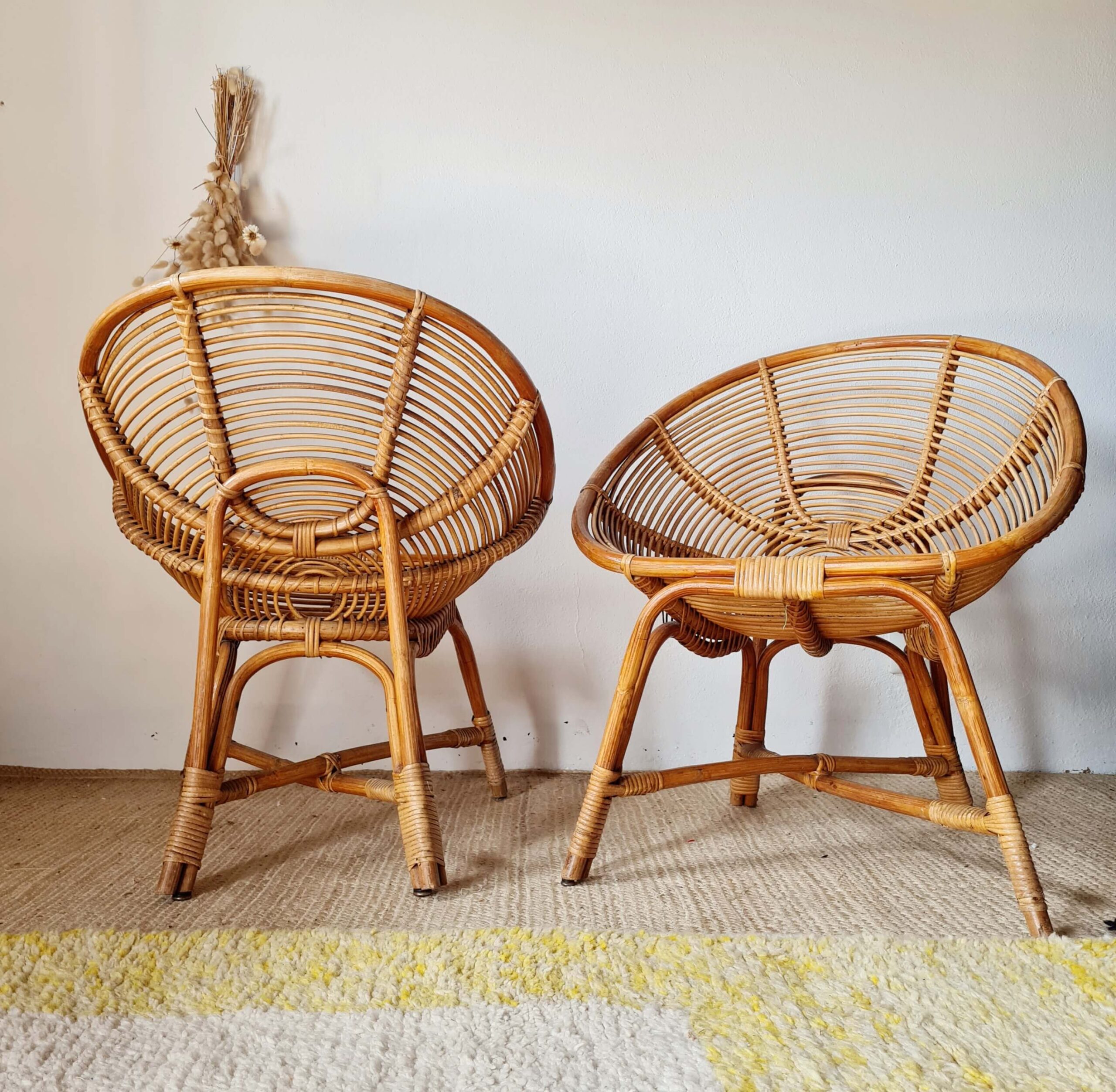 Paire de fauteuils vintage en rotin de style coquille disposés sur un tapis clair, esprit décoration bohème chic