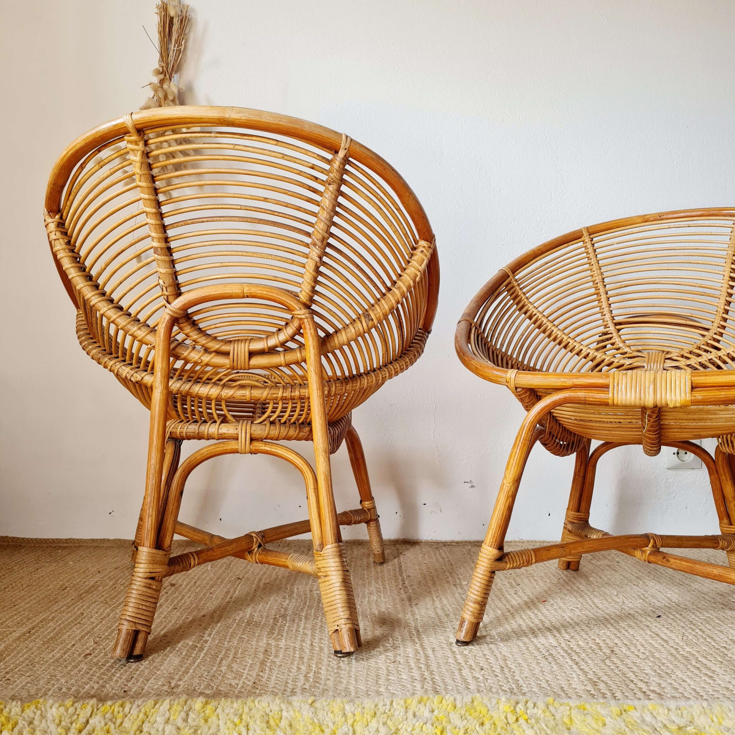 Vue arrière détaillée d'une paire de fauteuils en rotin vintage, montrant le travail de tressage et la structure solide des assises.