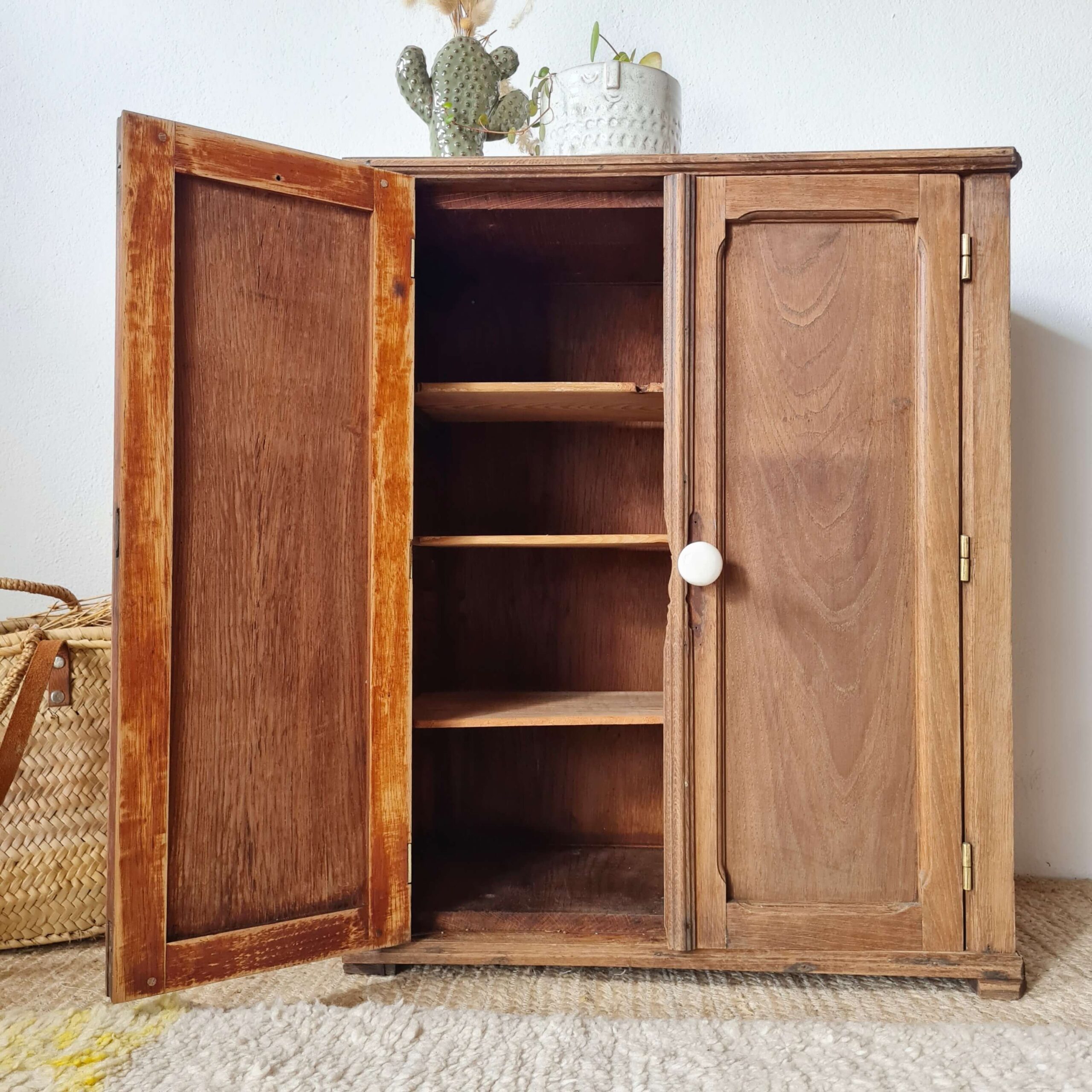 Petite armoire parisienne de style pharmacie en bois brut de face, avec une porte ouverte révélant ses étagères intérieures.