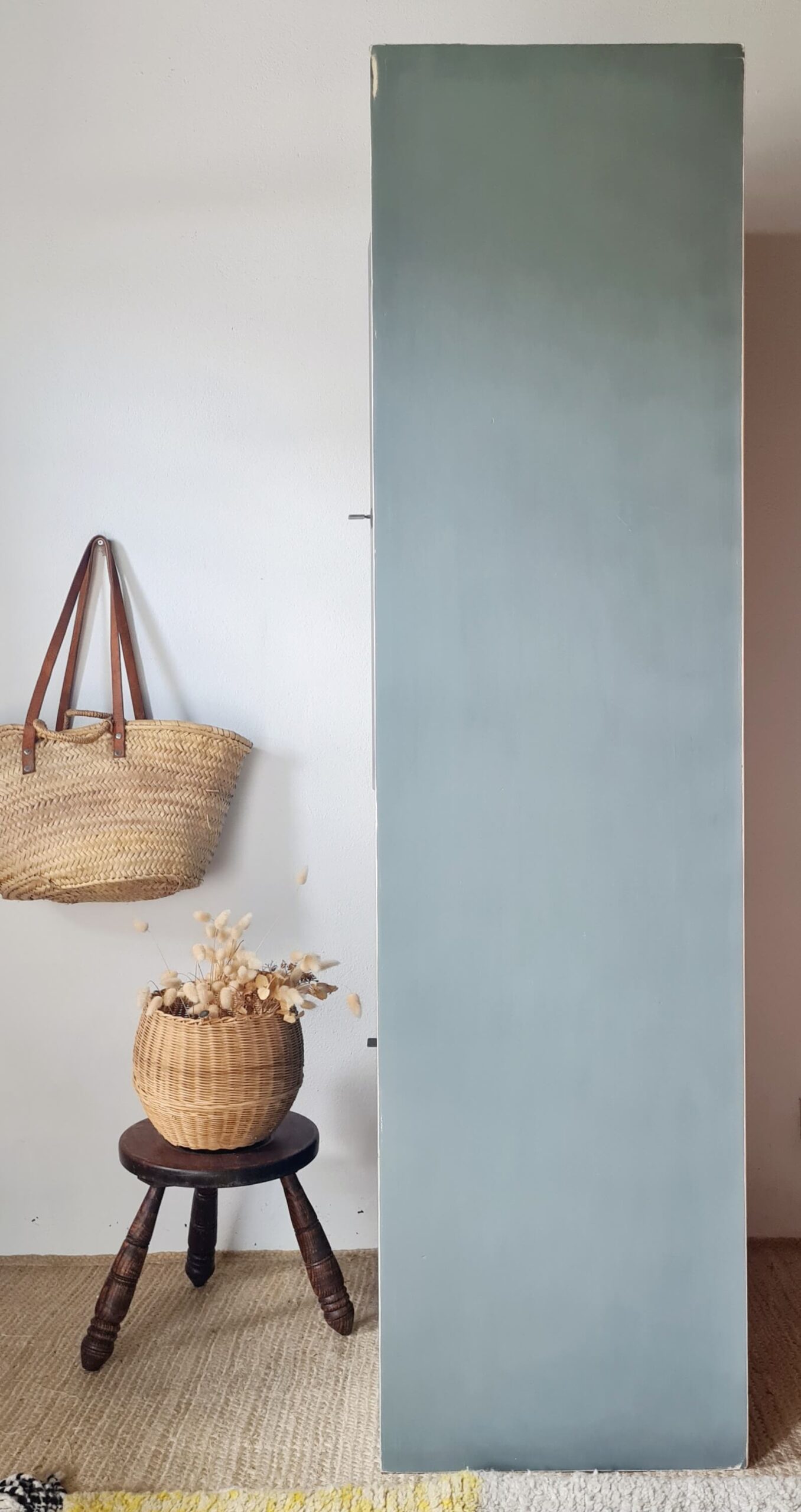 Vue de profil d'une armoire haute peinte en bleu, mettant en évidence ses lignes épurées et son intégration dans un intérieur bohème