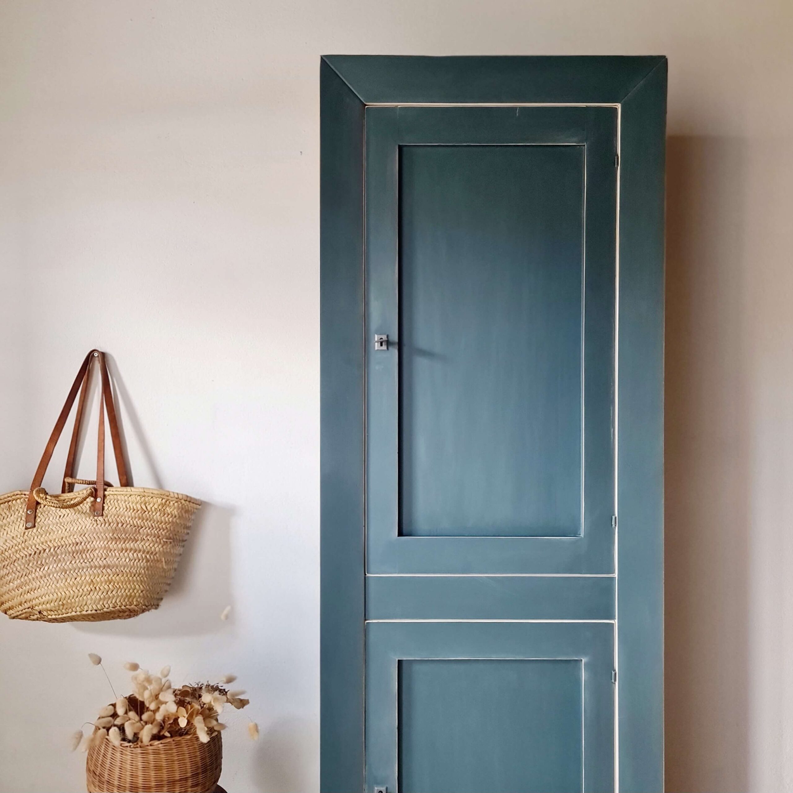 Meuble de rangement haut, armoire bleue au design épuré, mise en scène avec des accessoires naturels