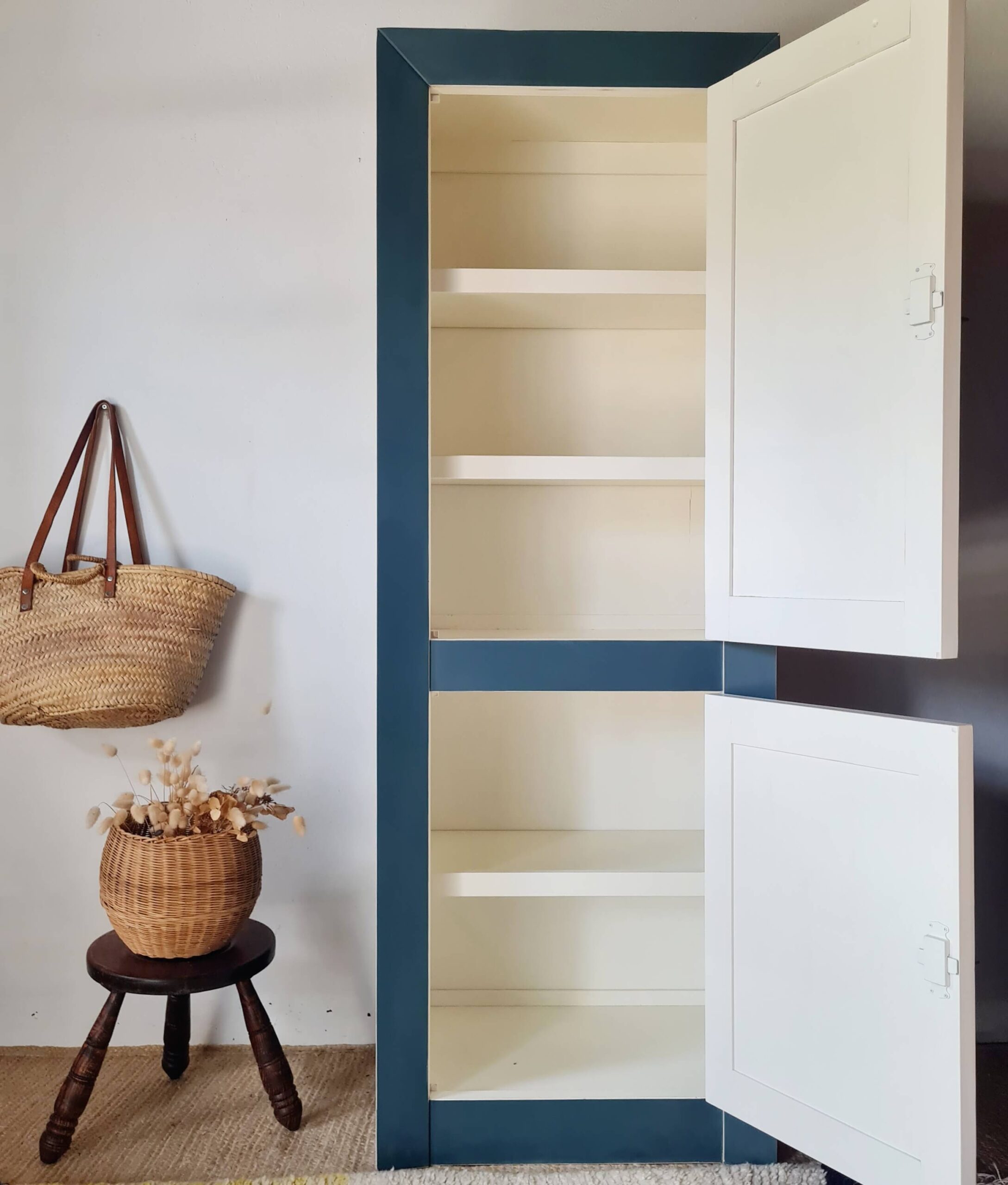 Armoire haute en bois massif peinte en bleu avec les portes ouvertes, révélant ses étagères de rangement intérieures
