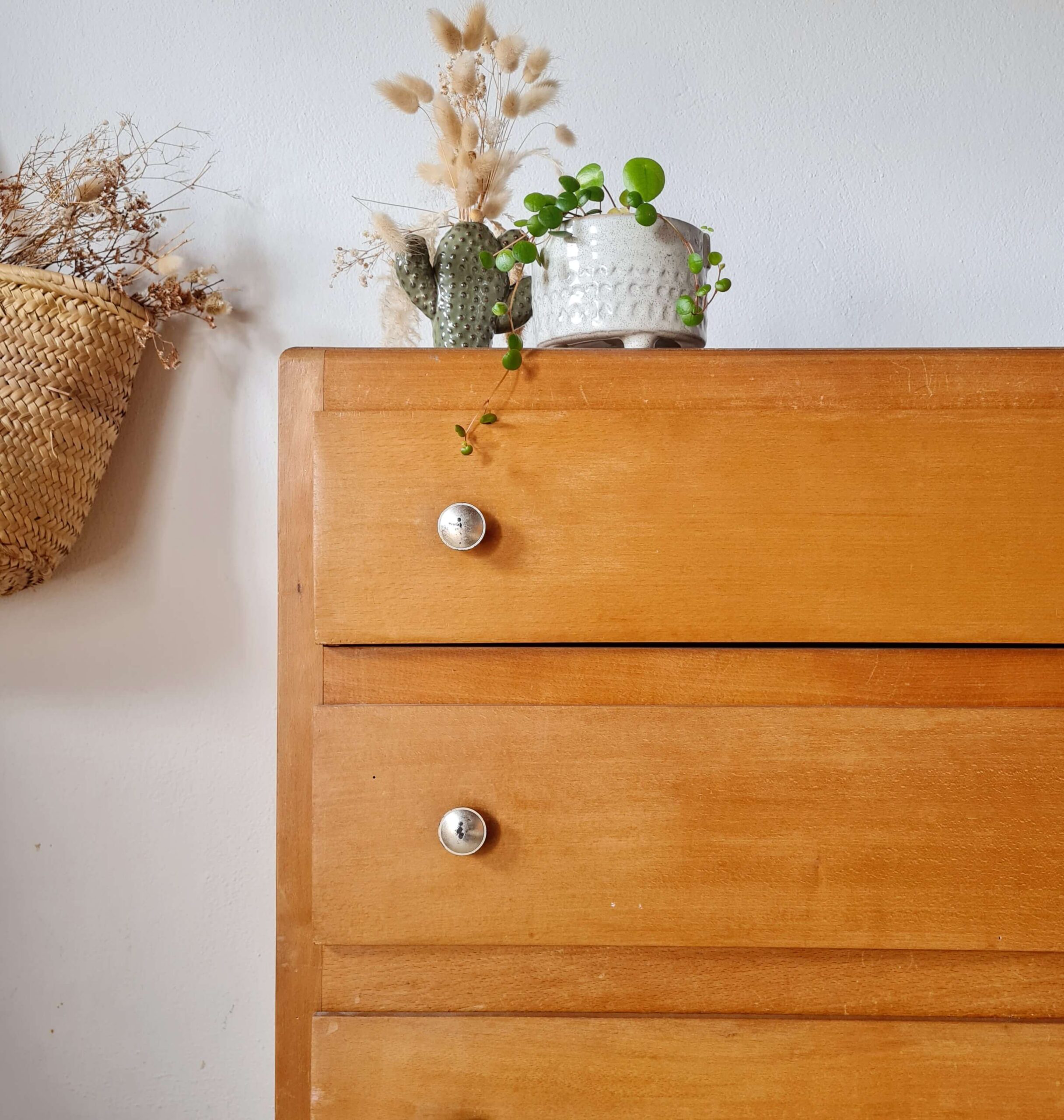 Détail de la façade en bois vernis et des poignées métalliques d'un meuble de rangement vintage.