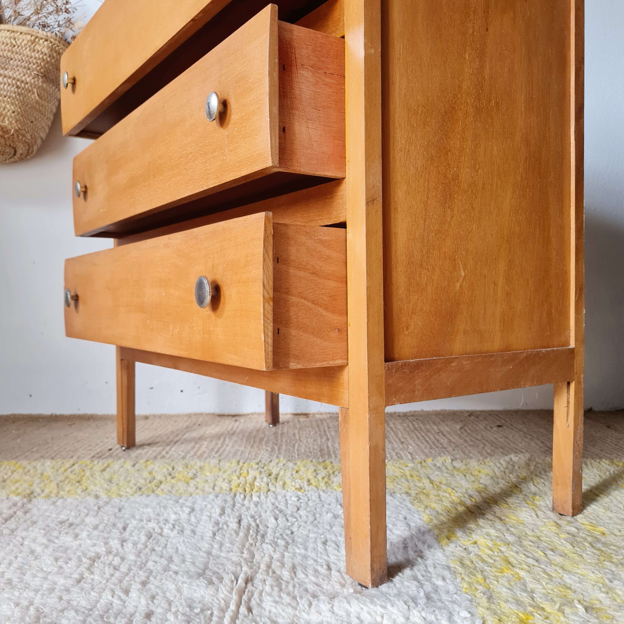 Vue de côté des tiroirs en bois ouverts d'une commode rétro des années 50.