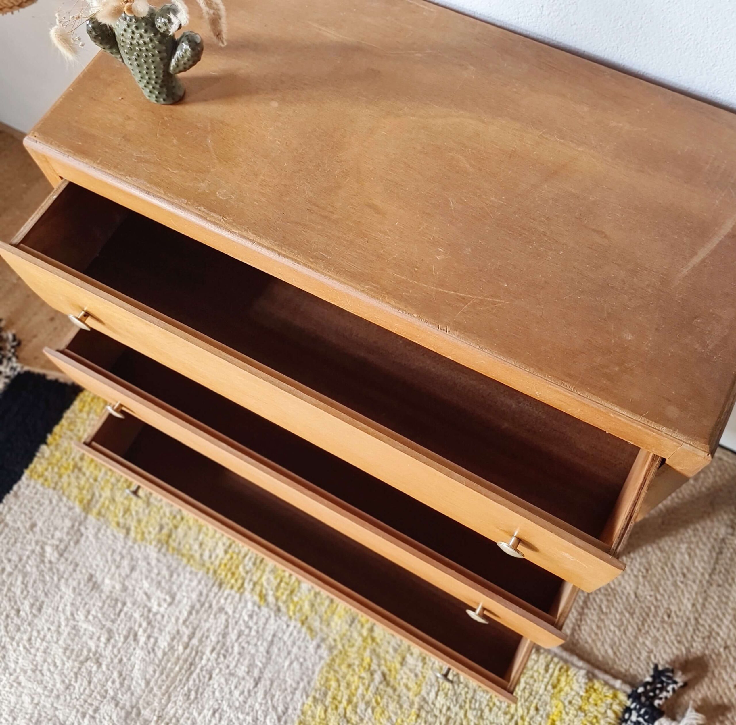 Vue du dessus d'une commode vintage avec ses trois tiroirs ouverts montrant l'espace de rangement intérieur.