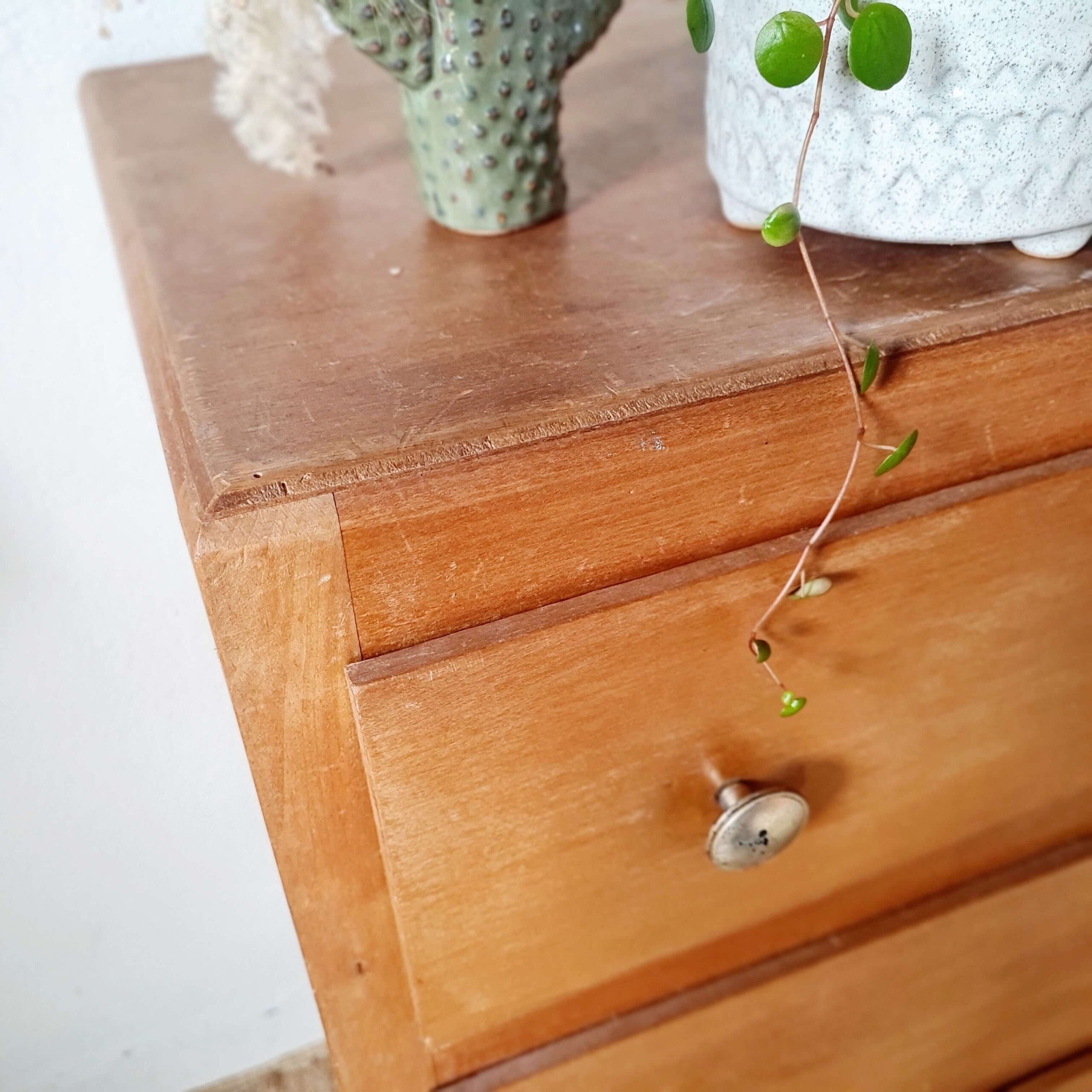 Angle de vue plongeant sur le plateau supérieur en bois patiné d'une commode ancienne.