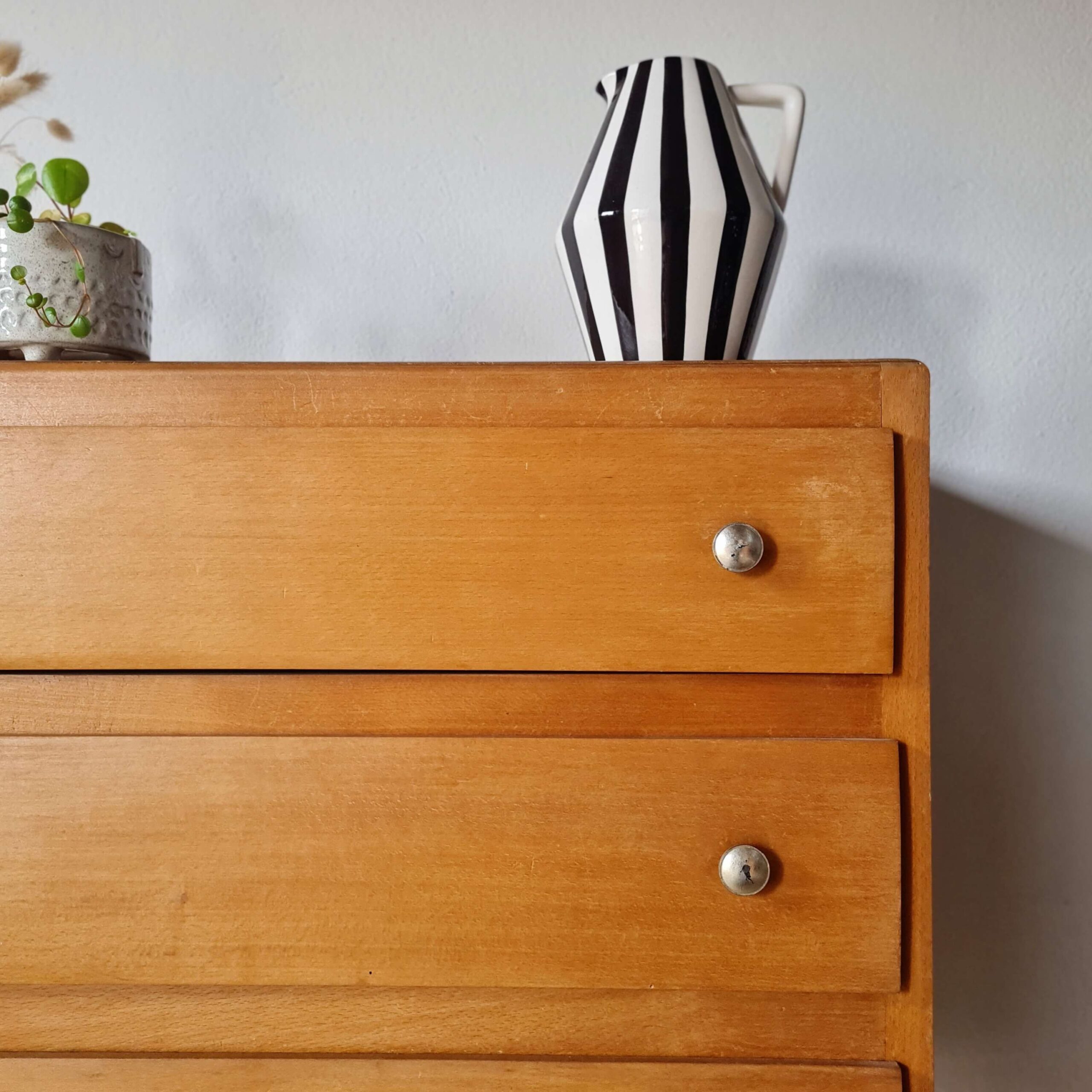 Partie supérieure droite d'une commode en bois avec un vase en céramique à rayures blanches et noires.