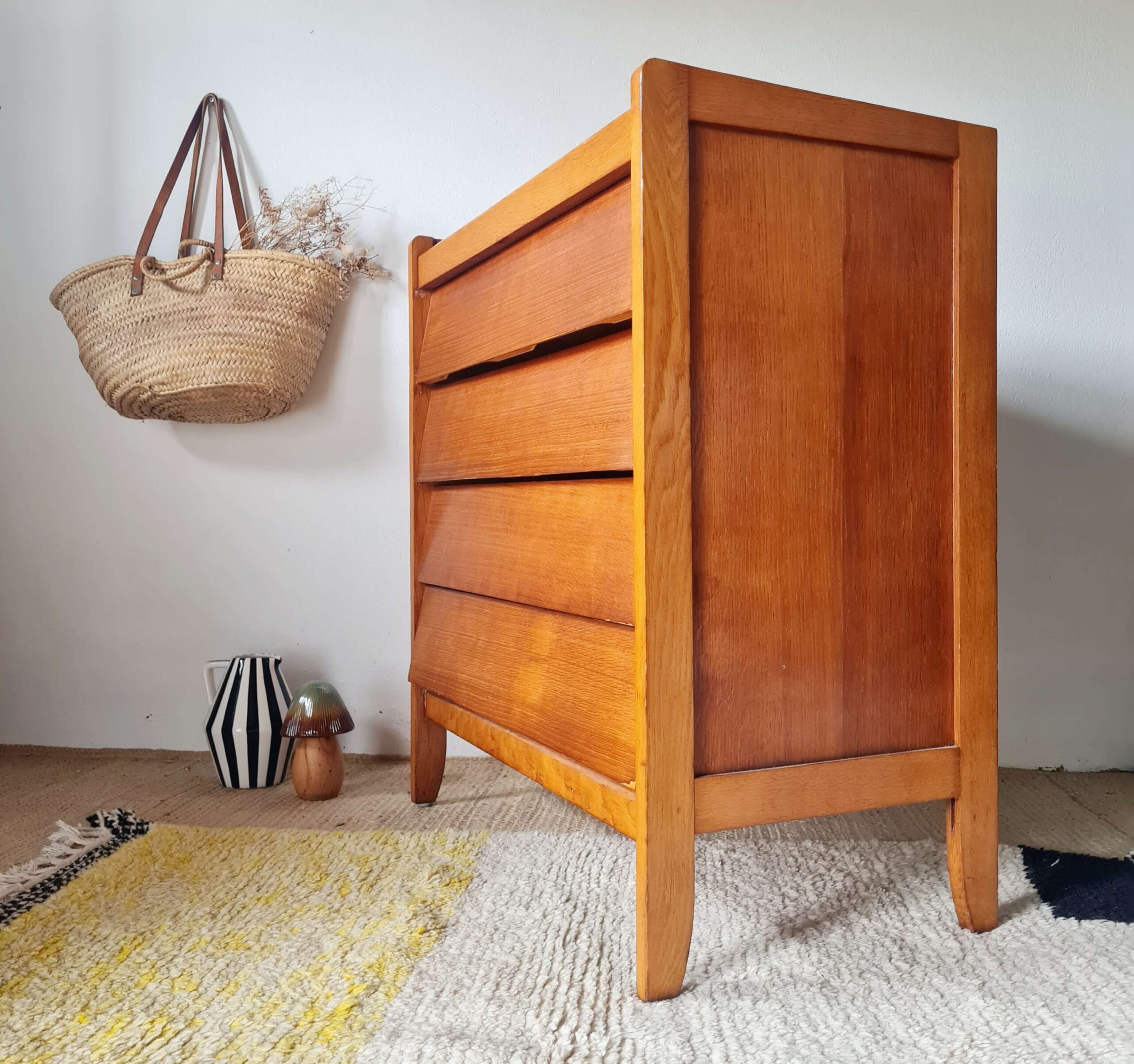 Commode vintage en chêne doré des années 60 vue de trois-quarts droit, mettant en valeur son profil et ses tiroirs inclinés, Factory Vintage.