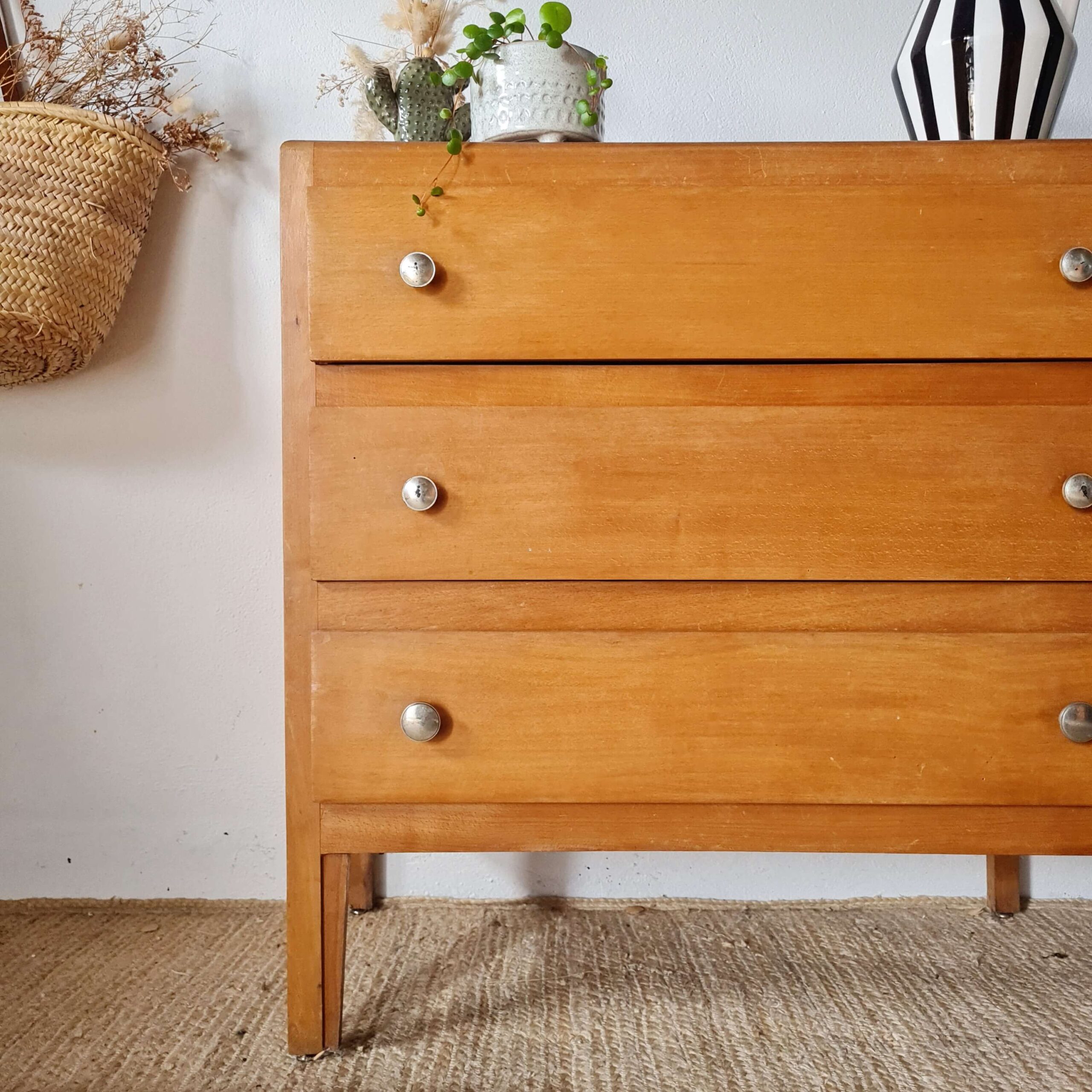 Décoration d'intérieur chaleureuse mettant en scène une commode en bois vintage sur un tapis graphique.