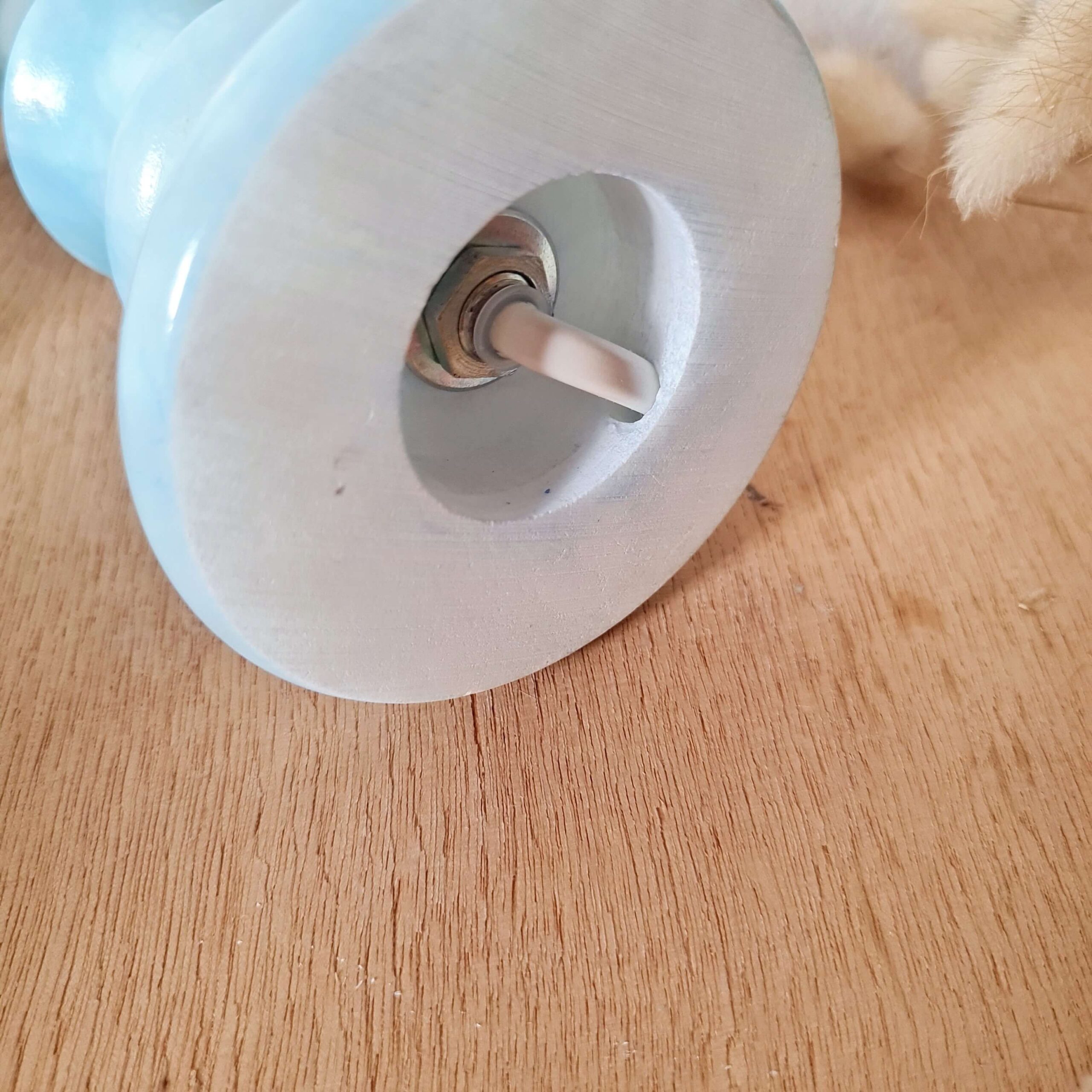 Vue du dessous de la base d'un pied de lampe vintage en opaline bleue montrant le système électrique