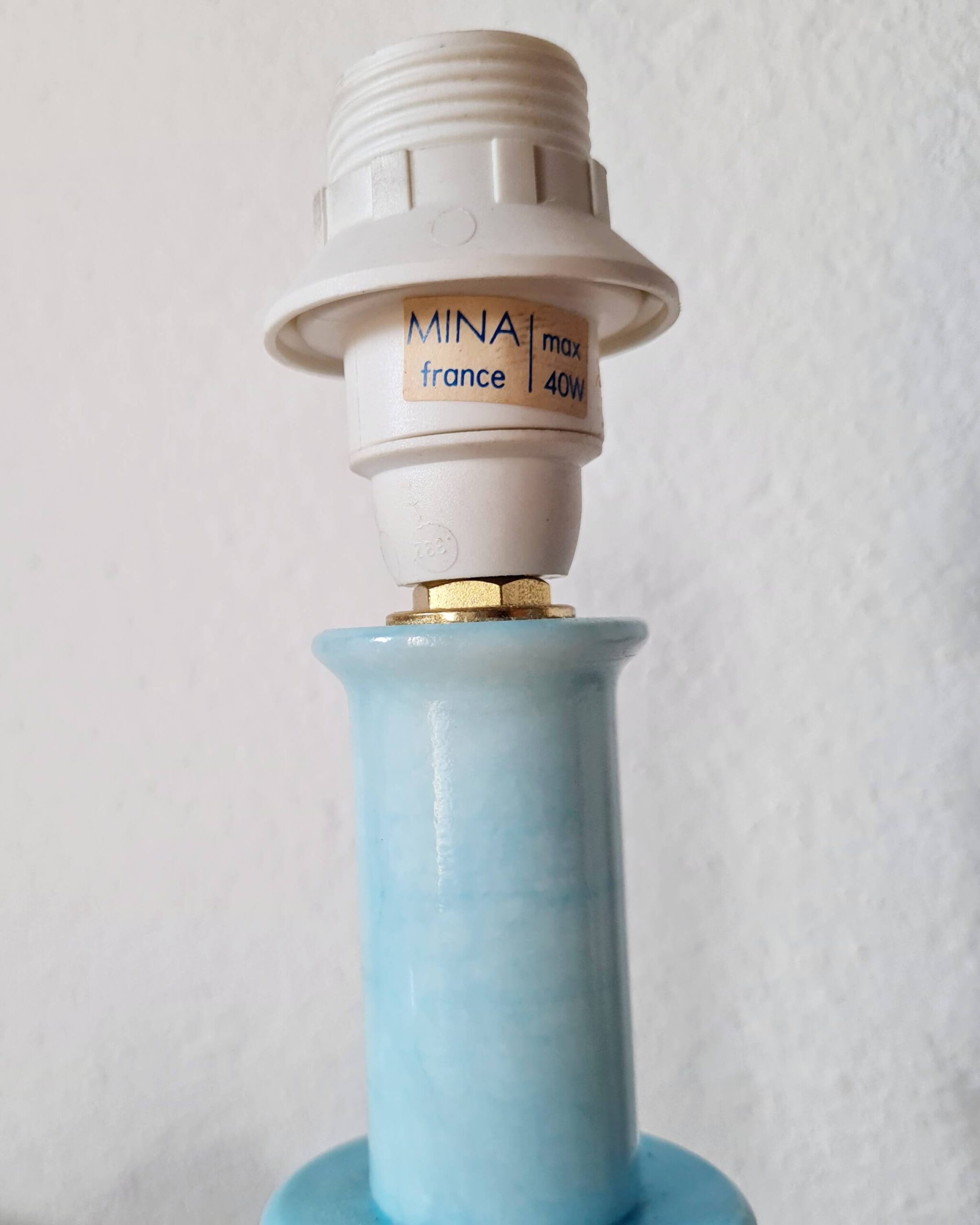Gros plan sur la douille blanche et l'étiquette d'origine Mina France max 40W d'un pied de lampe rétro