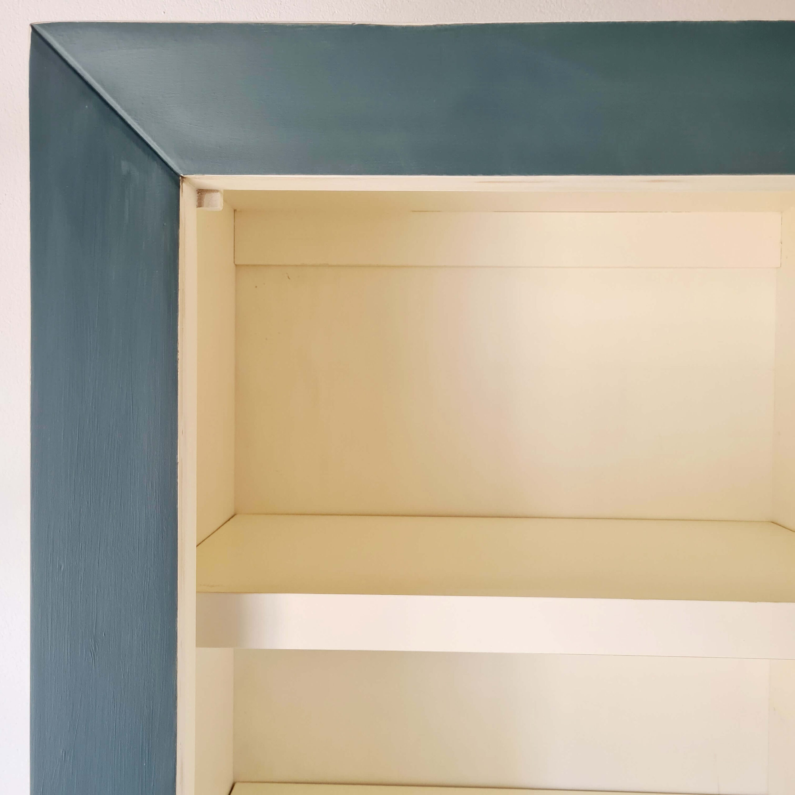 Vue détaillée de la structure intérieure et de l'encadrement d'une armoire peinte en bleu.