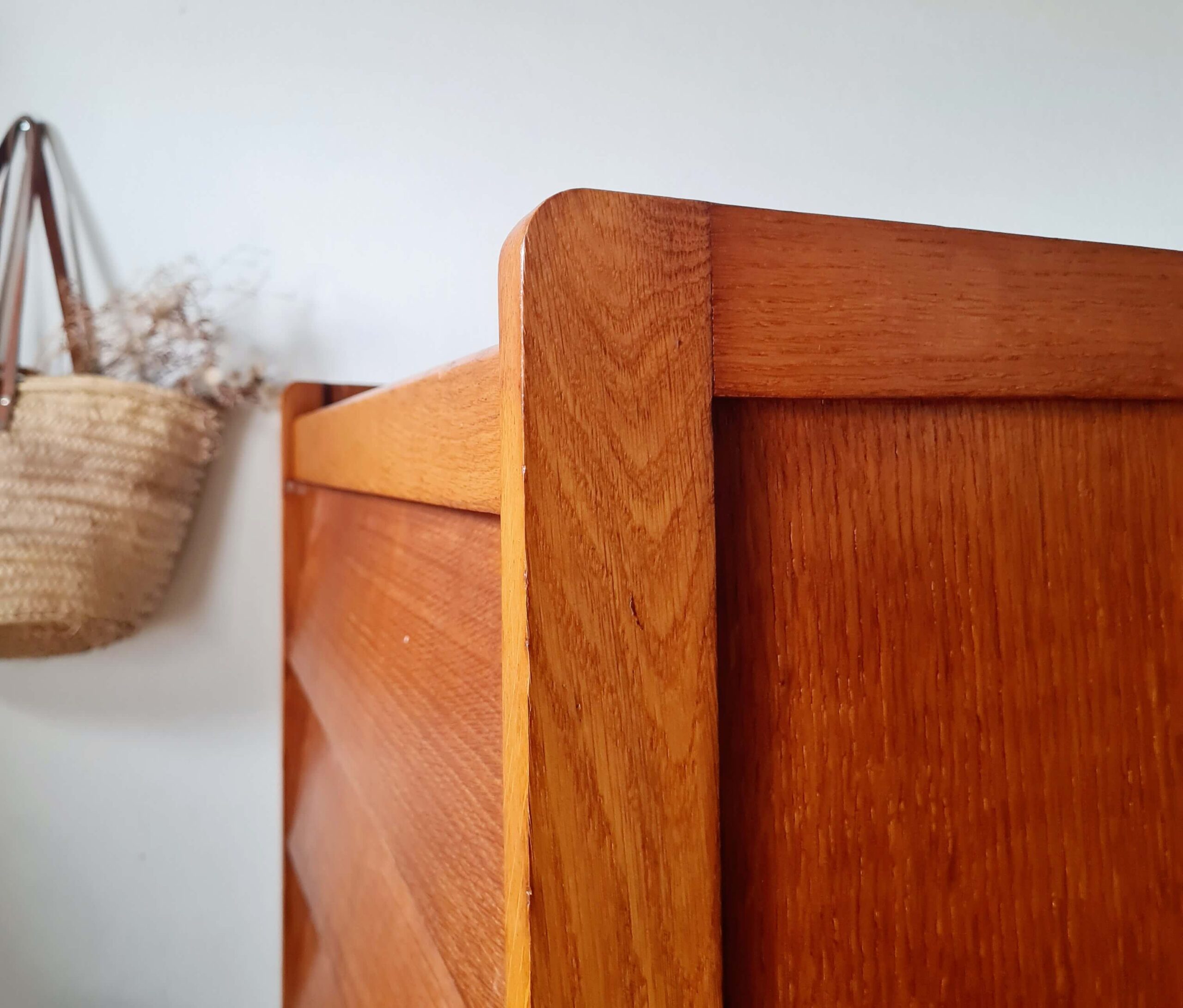 Détail des finitions du montant supérieur arrondi d'une commode scandinave vintage en chêne d'époque.