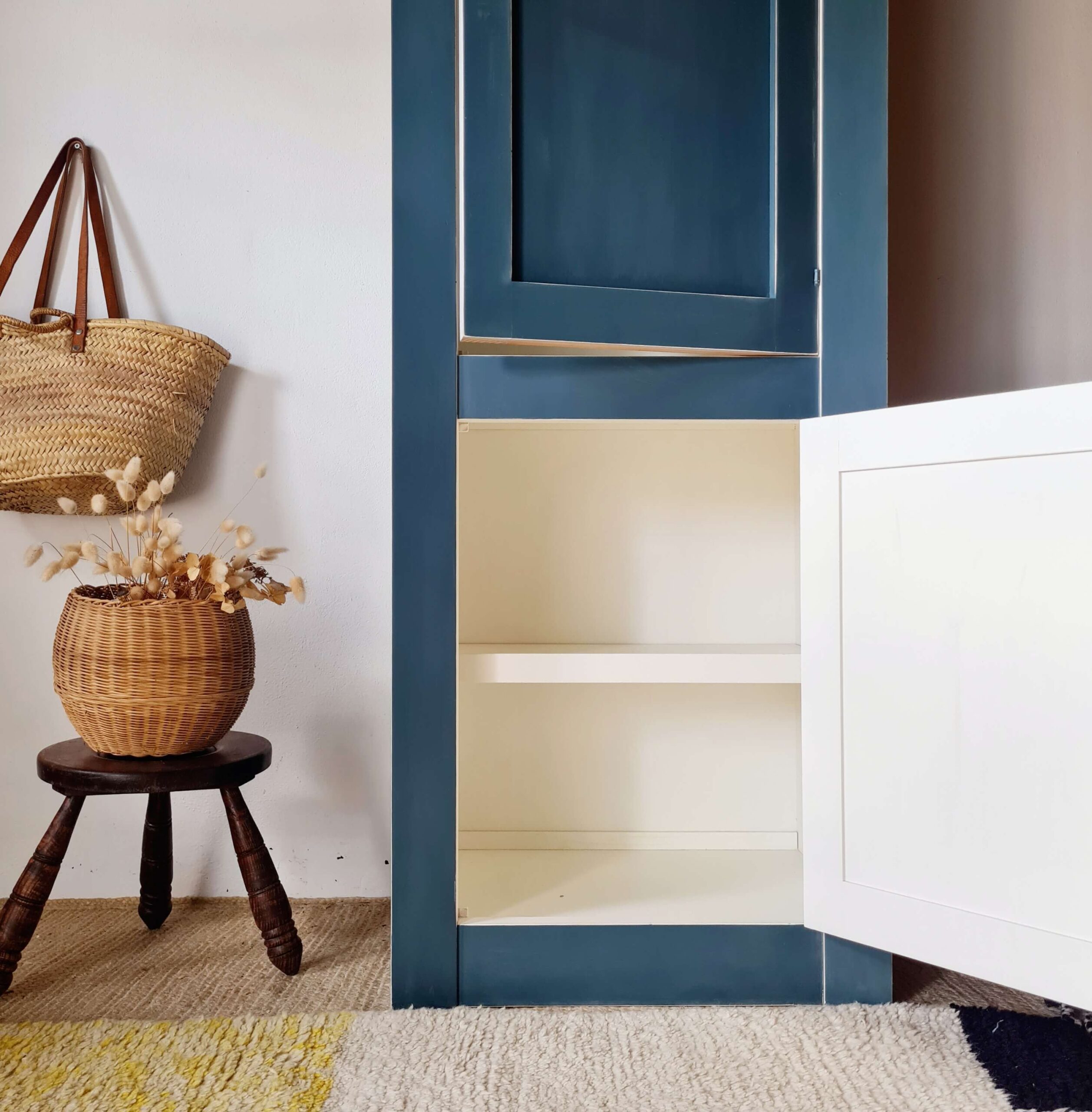 Vue intérieure d'une armoire bleue relookée, présentant des étagères blanches propres et spacieuses.