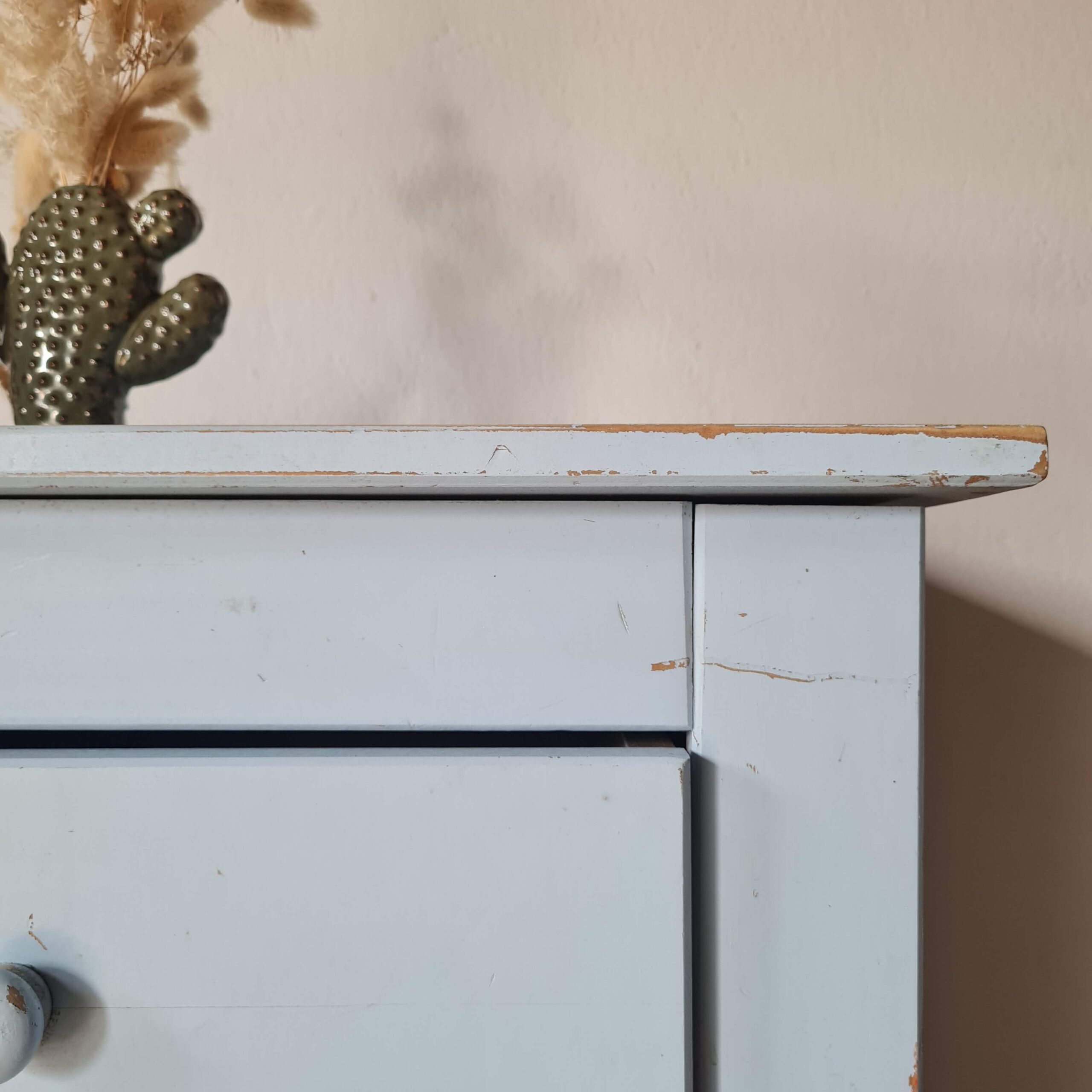 Gros plan sur les traces d'usure naturelle et l'assemblage du plateau supérieur d'un chevet bleu pastel.