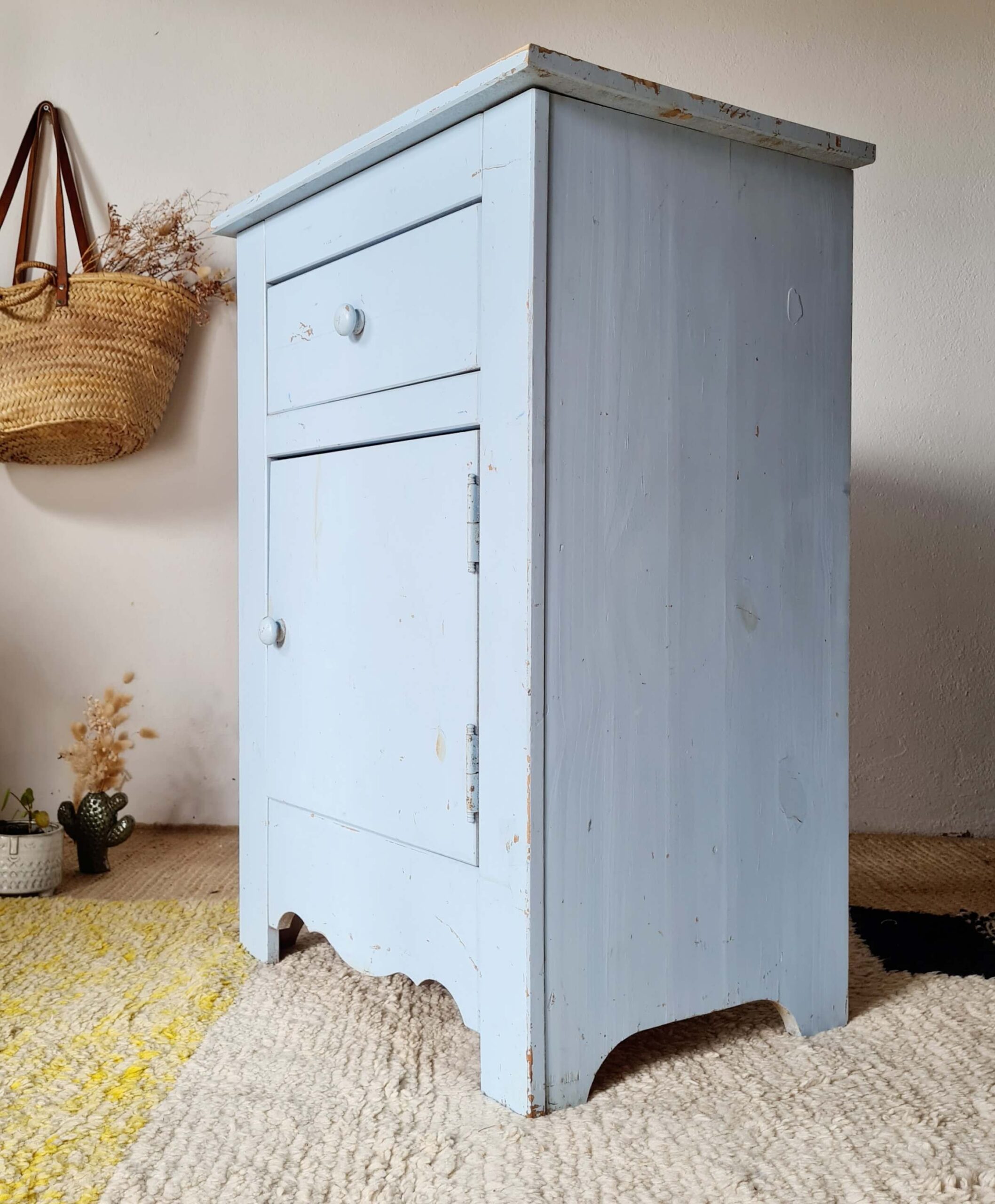 Vue de profil d'une petite commode de nuit bleu ciel en bois peint, idéale pour une déco brocante.