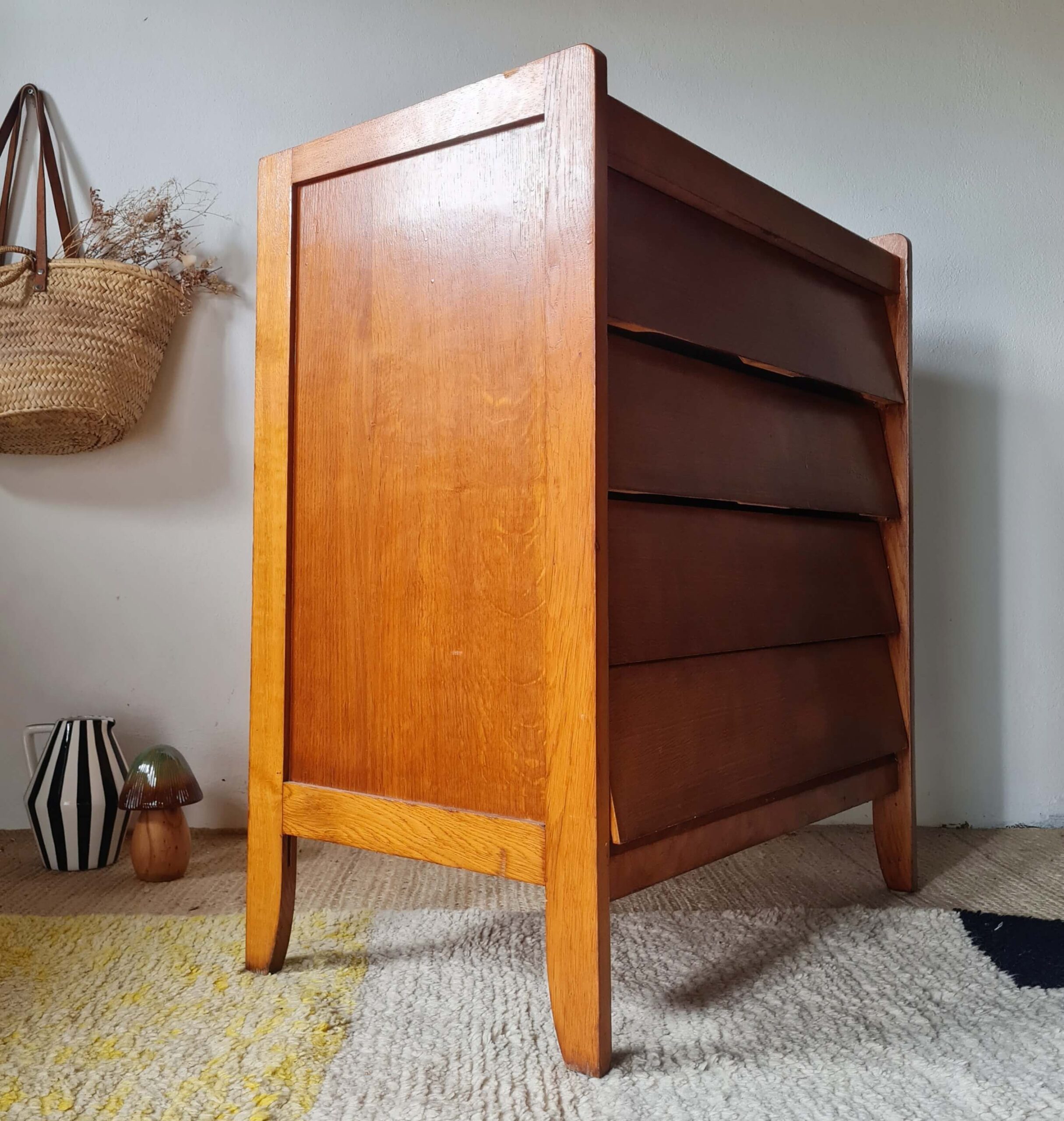 Meuble de rangement mid-century en bois clair vu de profil trois-quarts gauche, montrant la structure des tiroirs biseautés.