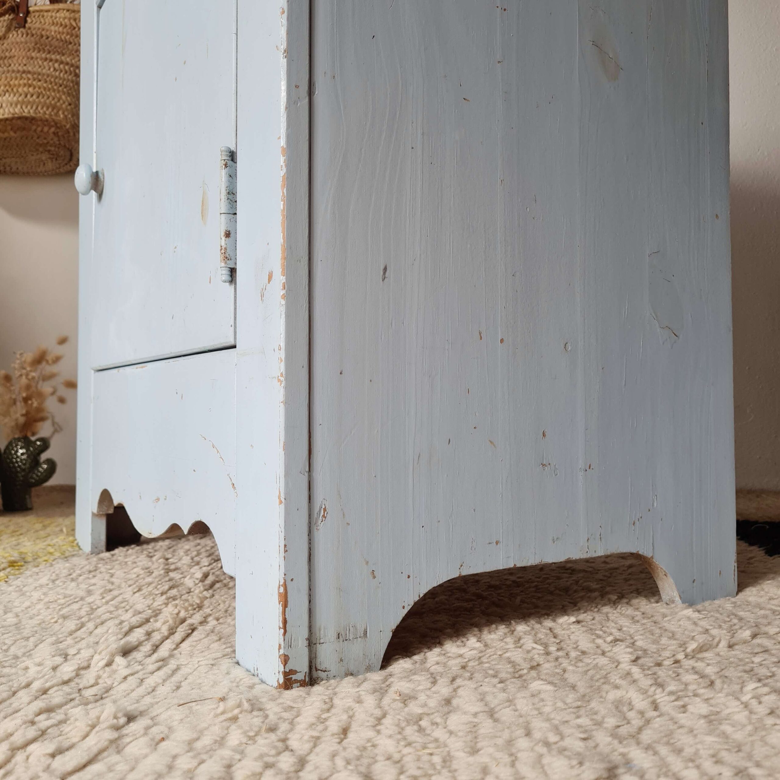 Détail de la découpe ondulée du bas de la table de chevet et de sa peinture patinée par le temps.