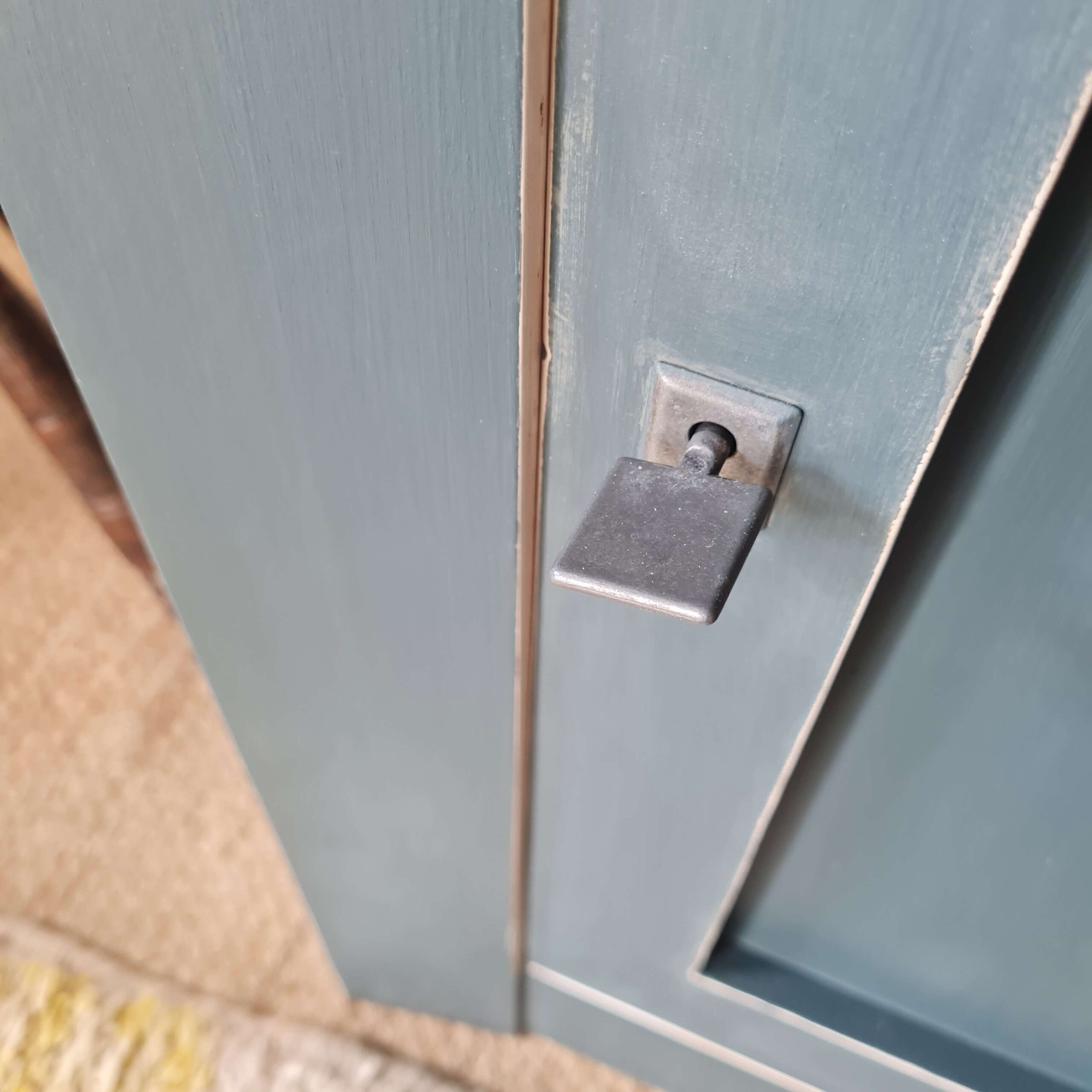 Détail de la poignée de fermeture d'une armoire bleue relookée, soulignant le travail artisanal du meuble
