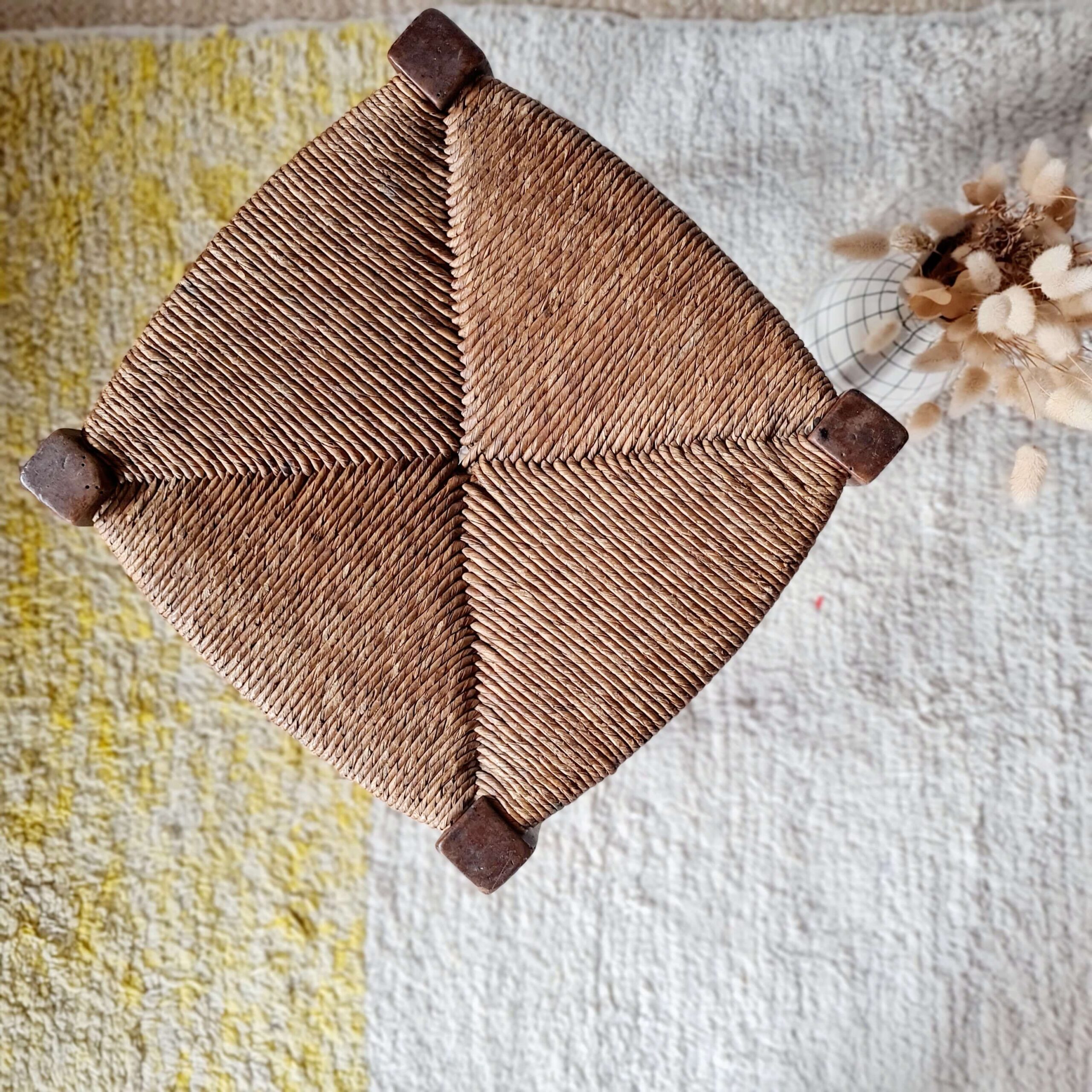 Vue du dessus d'un tabouret vintage montrant le détail de l'assise en paille tressée de manière traditionnelle en quatre triangles.