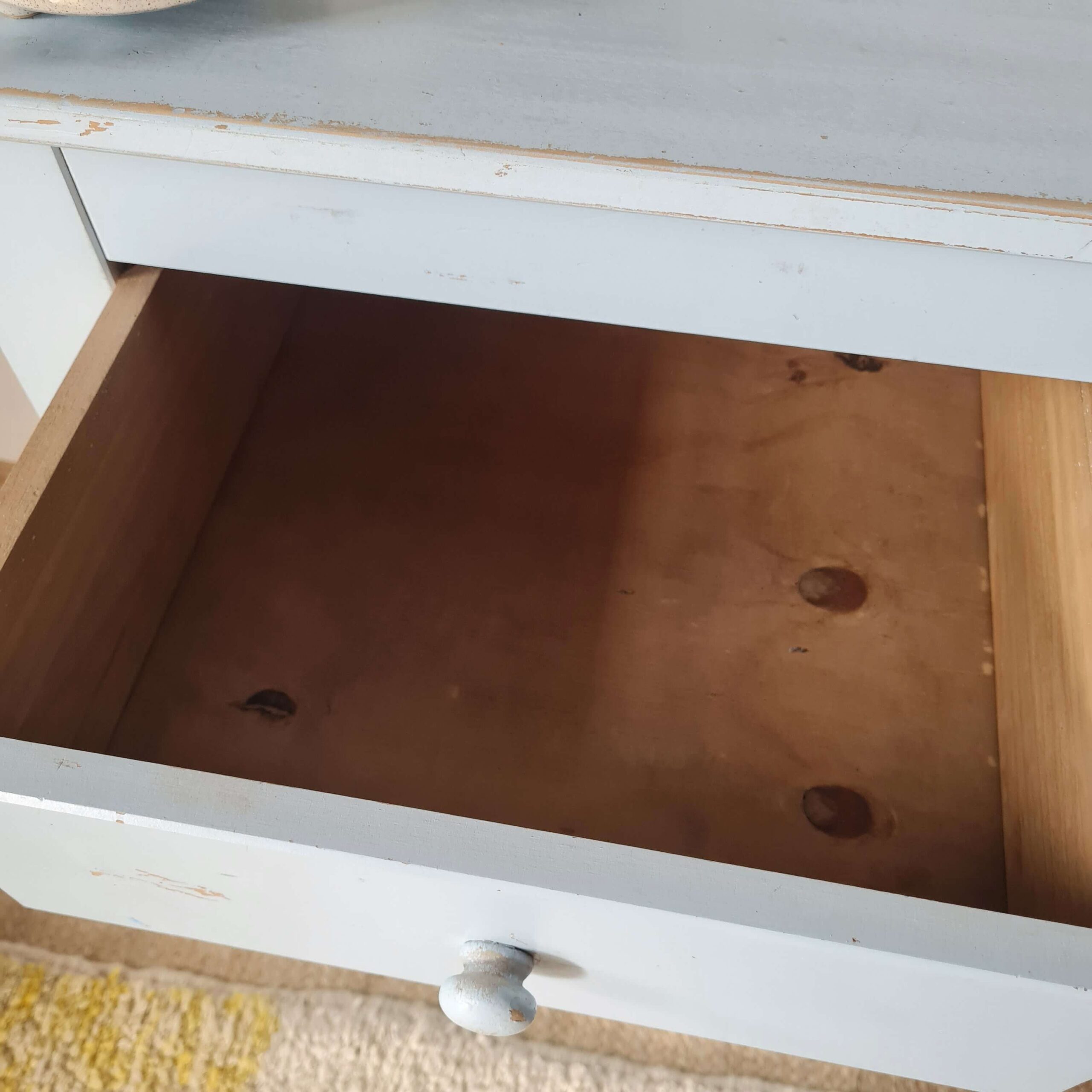 Vue plongeante de l'intérieur en bois brut d'un tiroir ouvert appartenant à la table de nuit vintage.