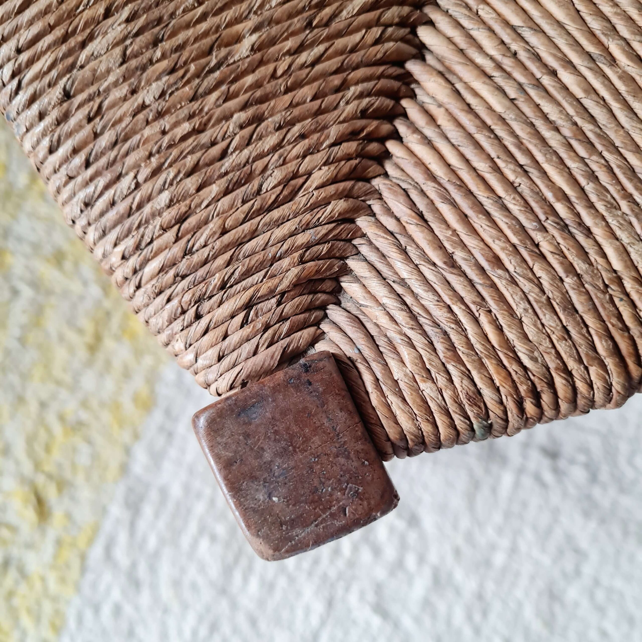Gros plan sur le paillage traditionnel de l'assise d'un tabouret en bois vintage.