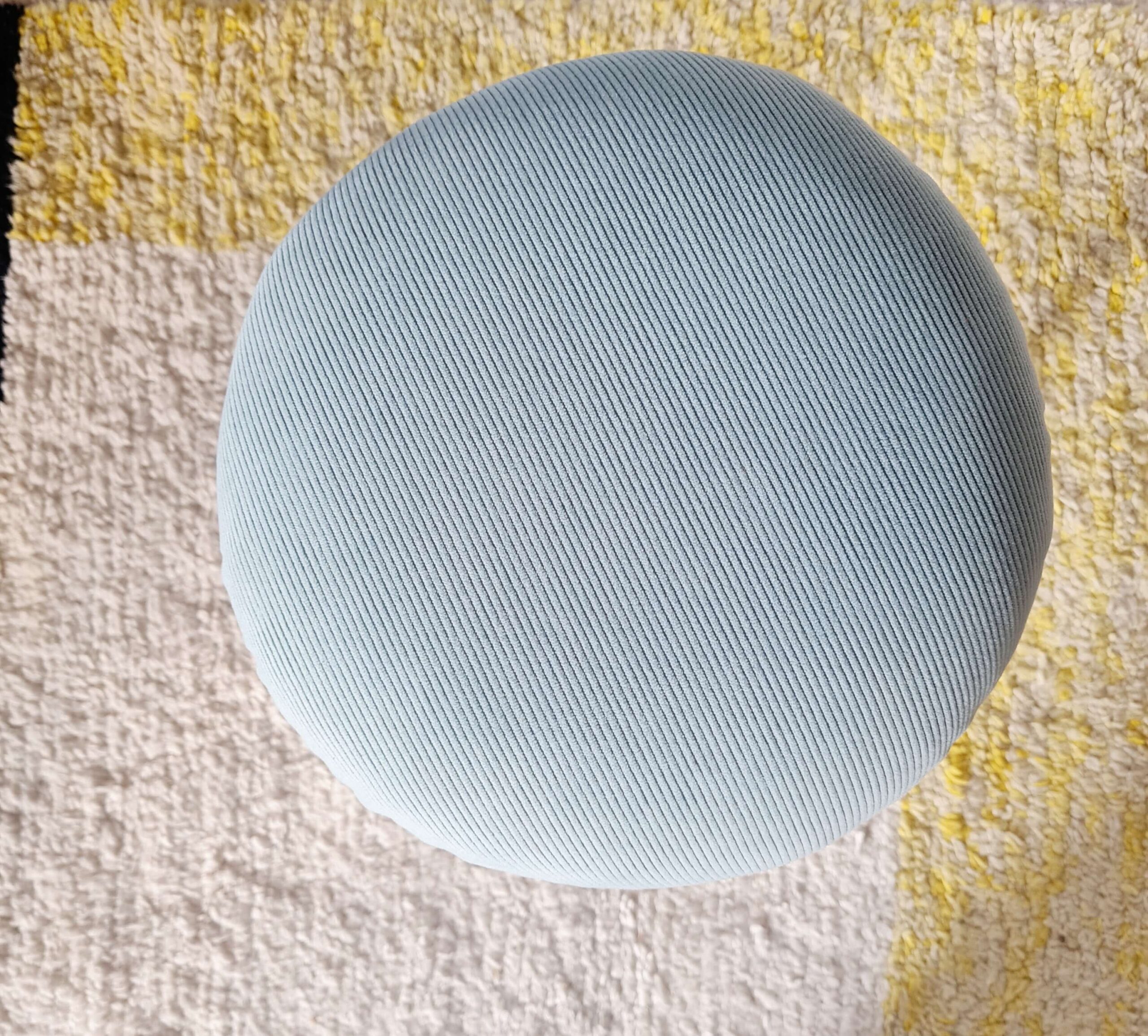 Vue du dessus de l'assise ronde en velours côtelé bleu clair d'un tabouret vintage.