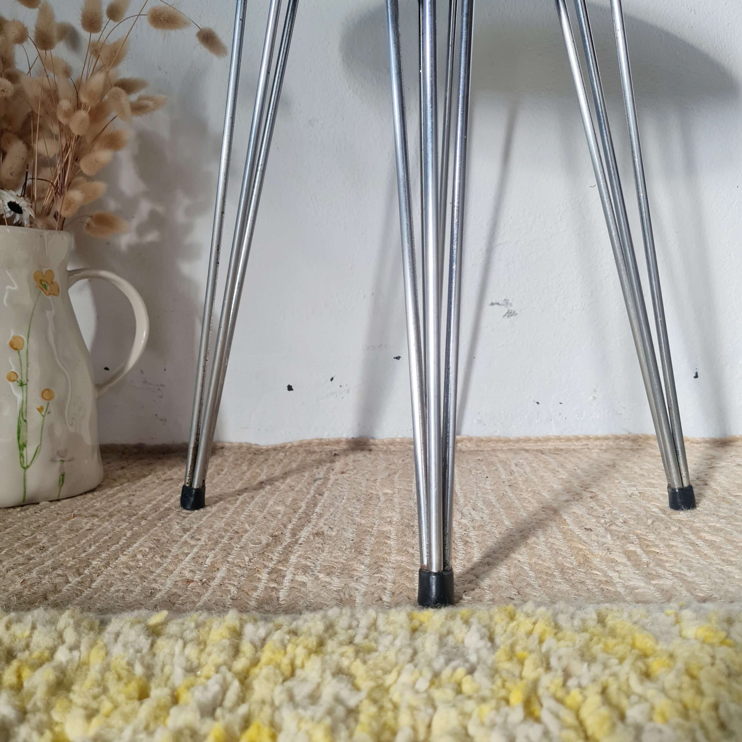 Gros plan sur les embouts et les pieds en métal chromé d'un tabouret vintage.