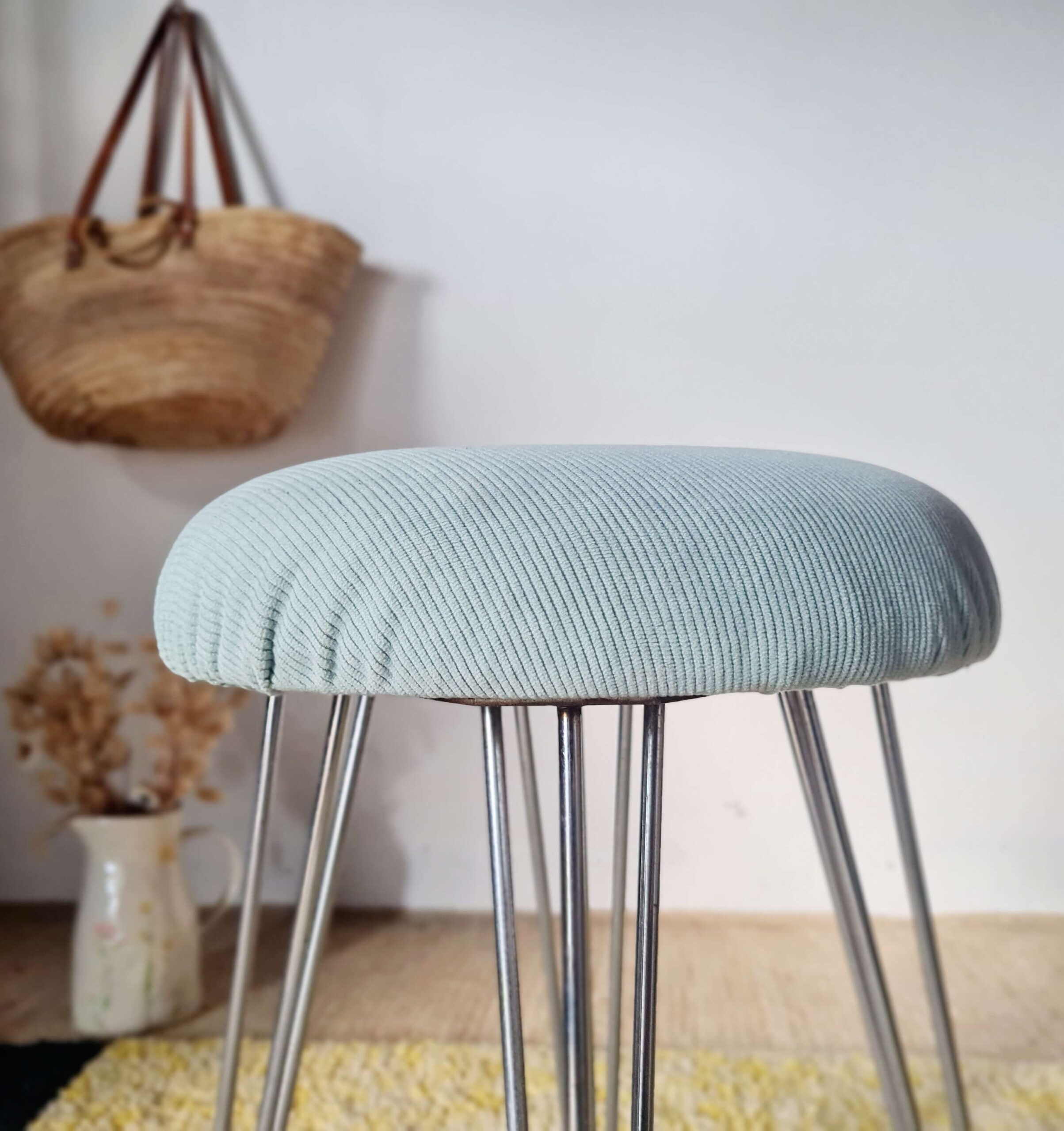 Gros plan sur les fixations et la structure en métal du tabouret vintage sous son assise en velours.