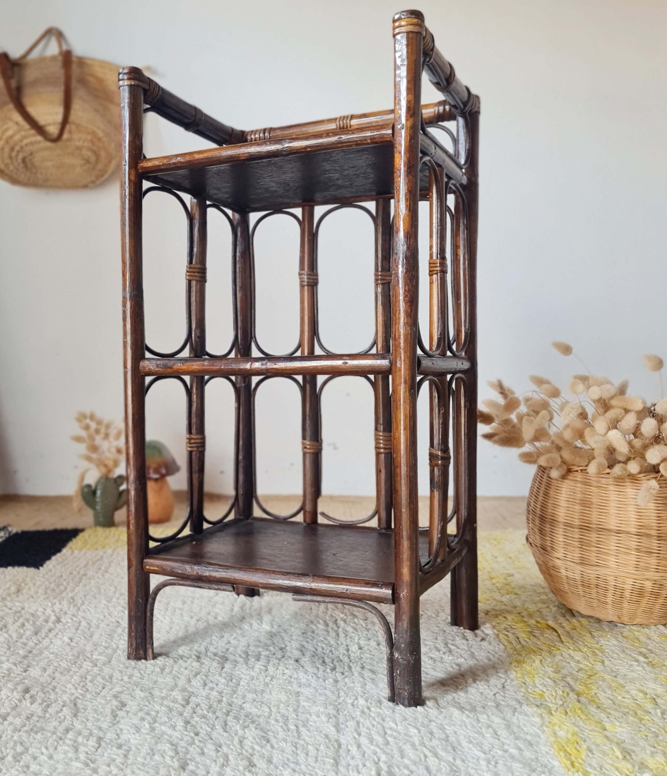 Vue de face en contre-plongée d'une étagère en rotin foncé dans un intérieur à la décoration bohème.