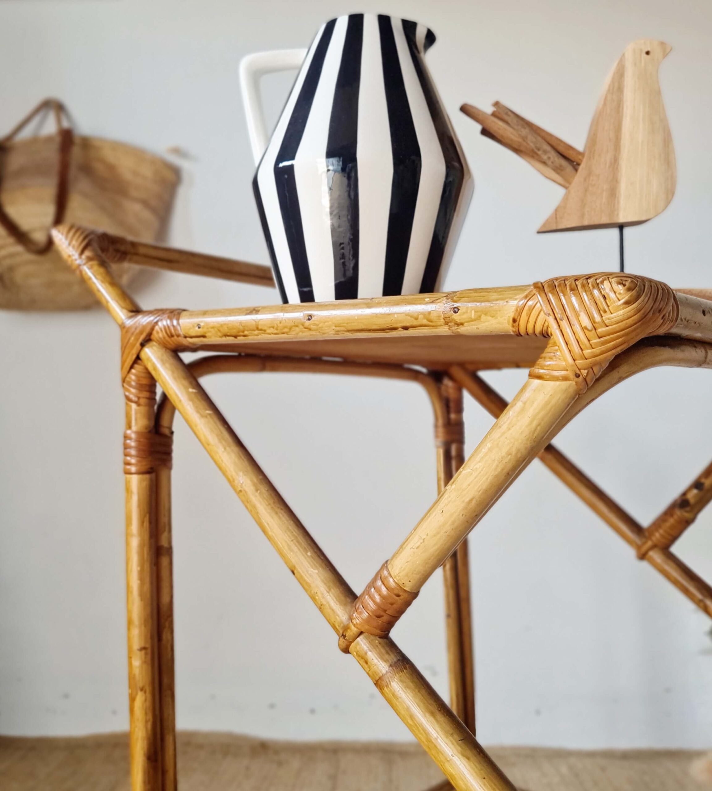 Vue de profil de la structure croisée en rotin d'une desserte de bar vintage avec accessoires.