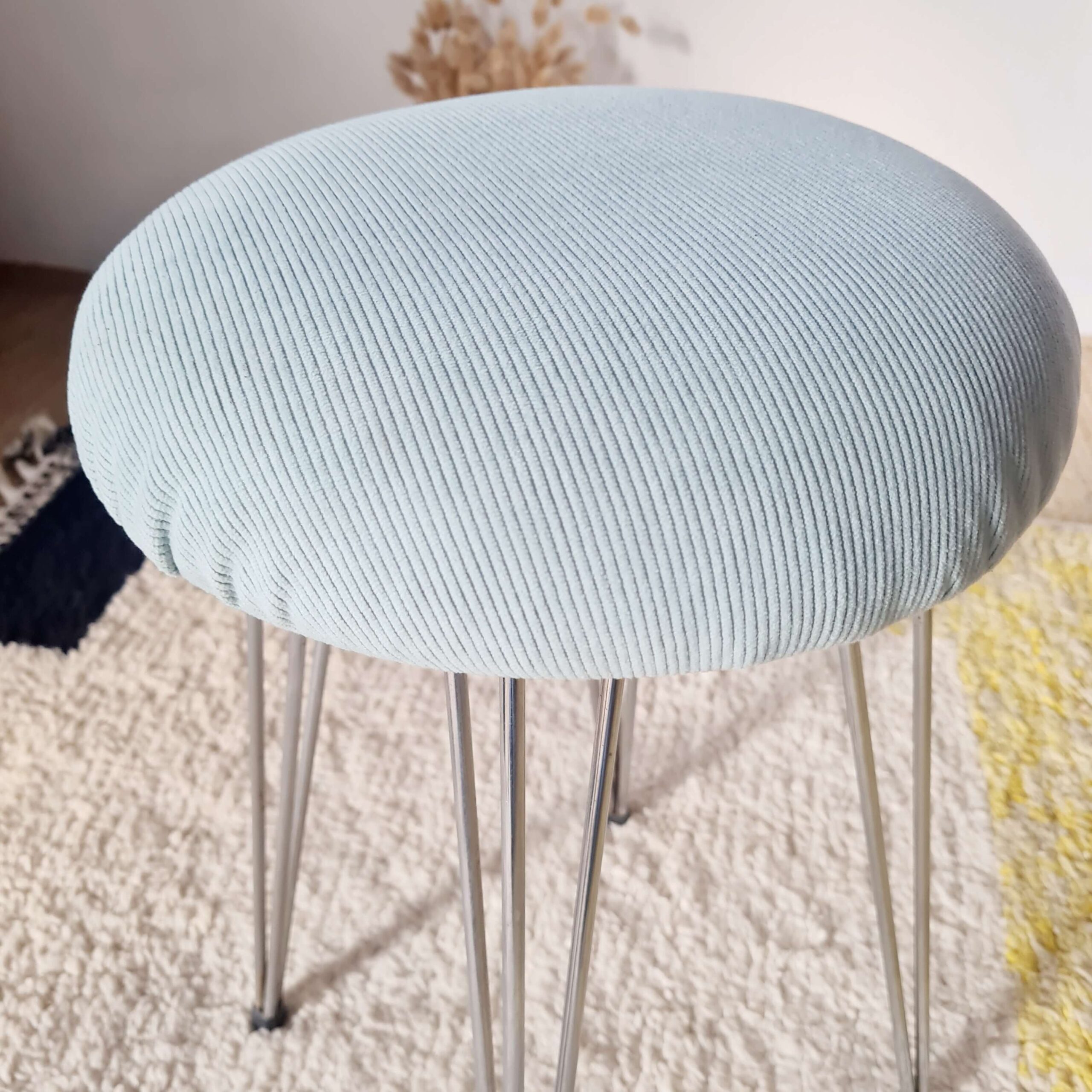 Gros plan serré sur la texture des rayures du velours côtelé bleu clair de l'assise.